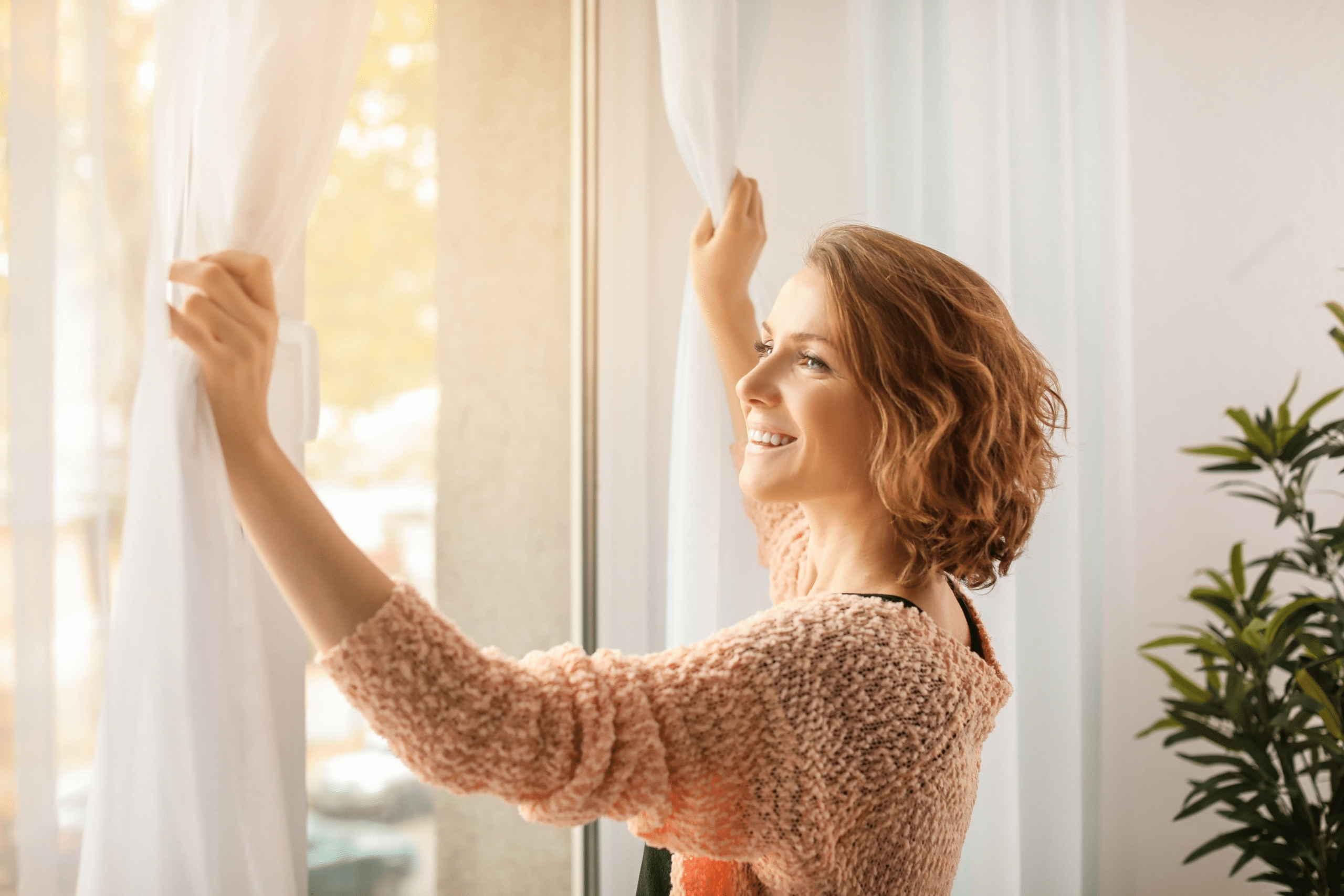 Person opening curtains to access window.