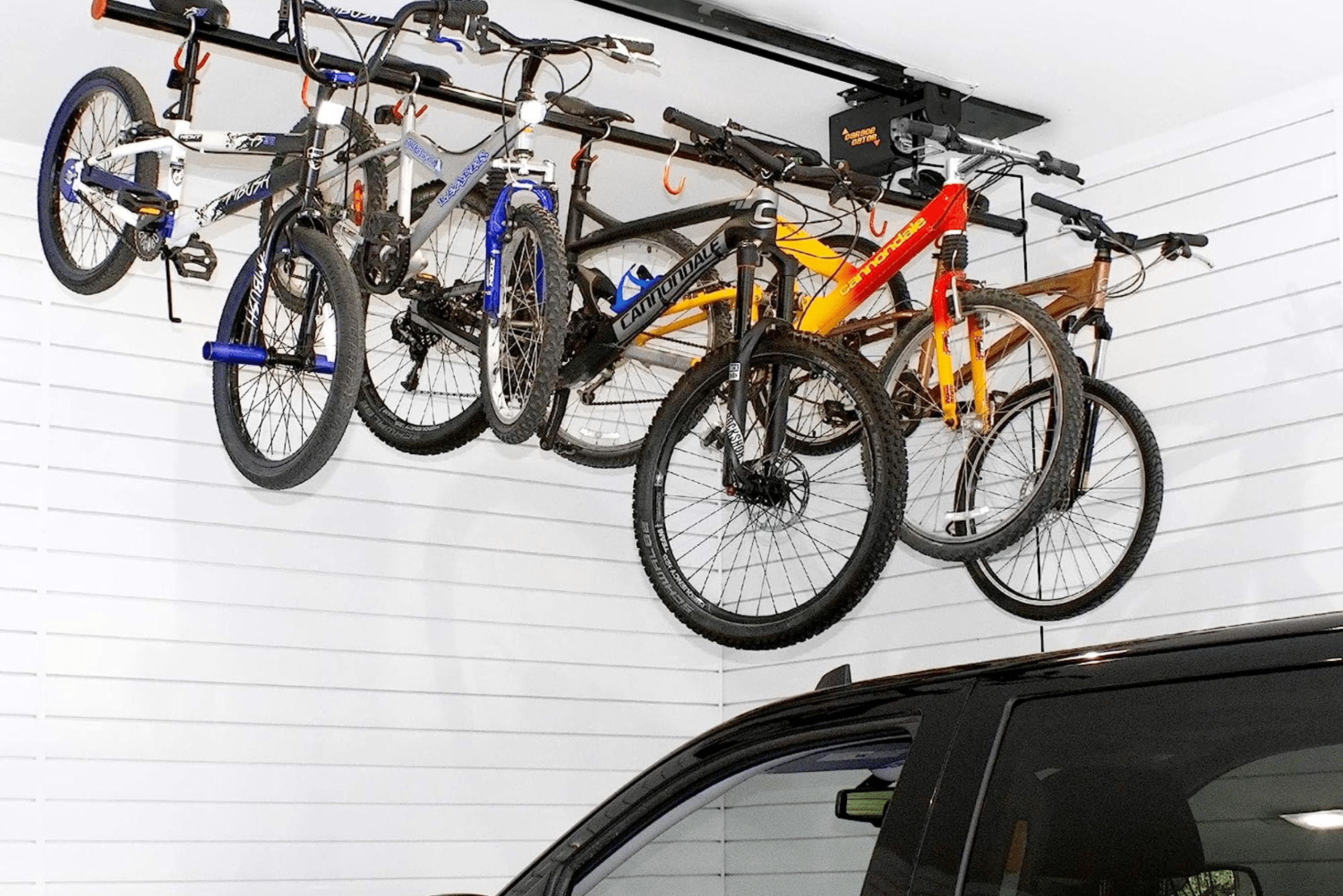 Multiple bikes mounted on a ceiling garage bike rack on top of a car.