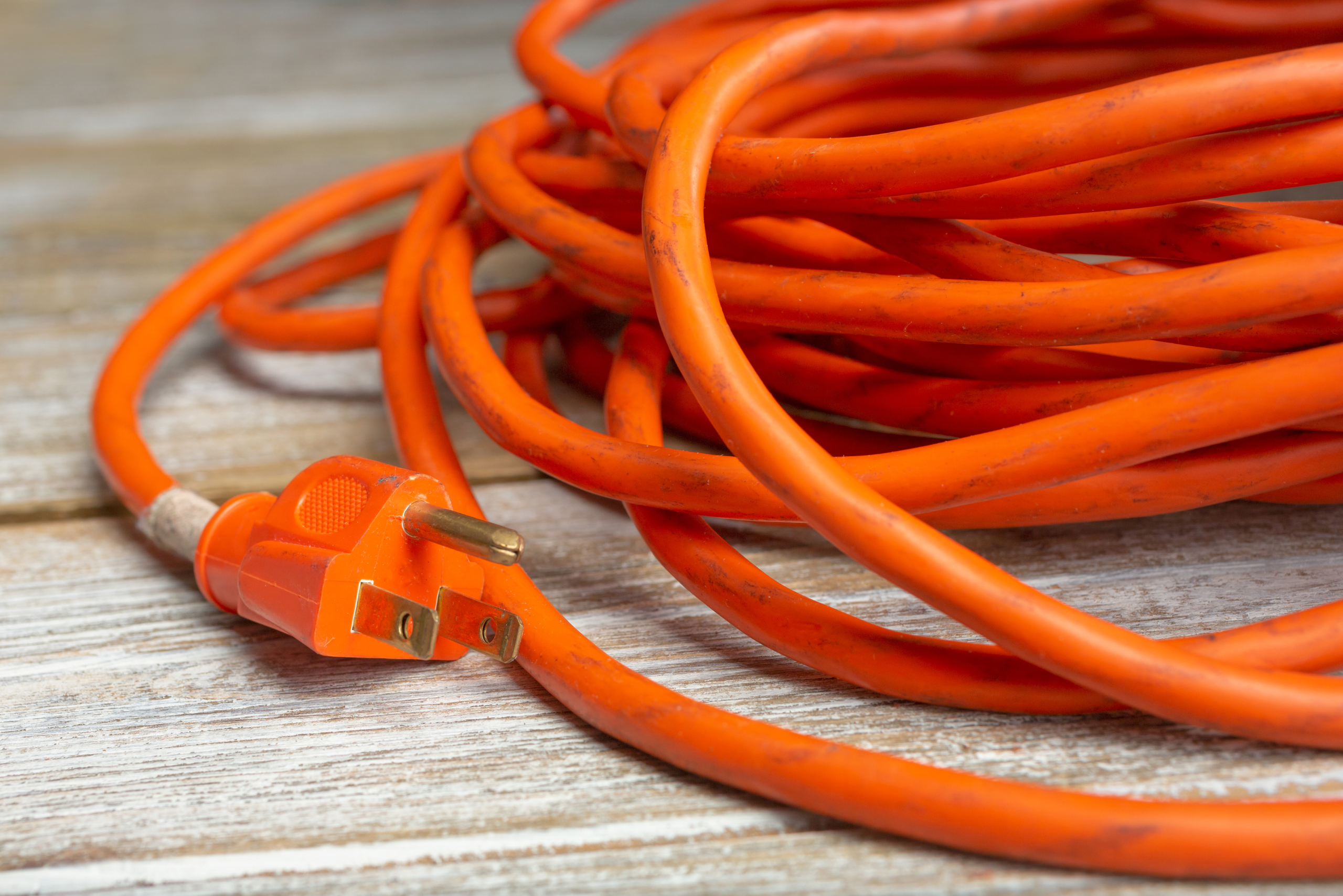 Orange extension cord on a wooden floor.