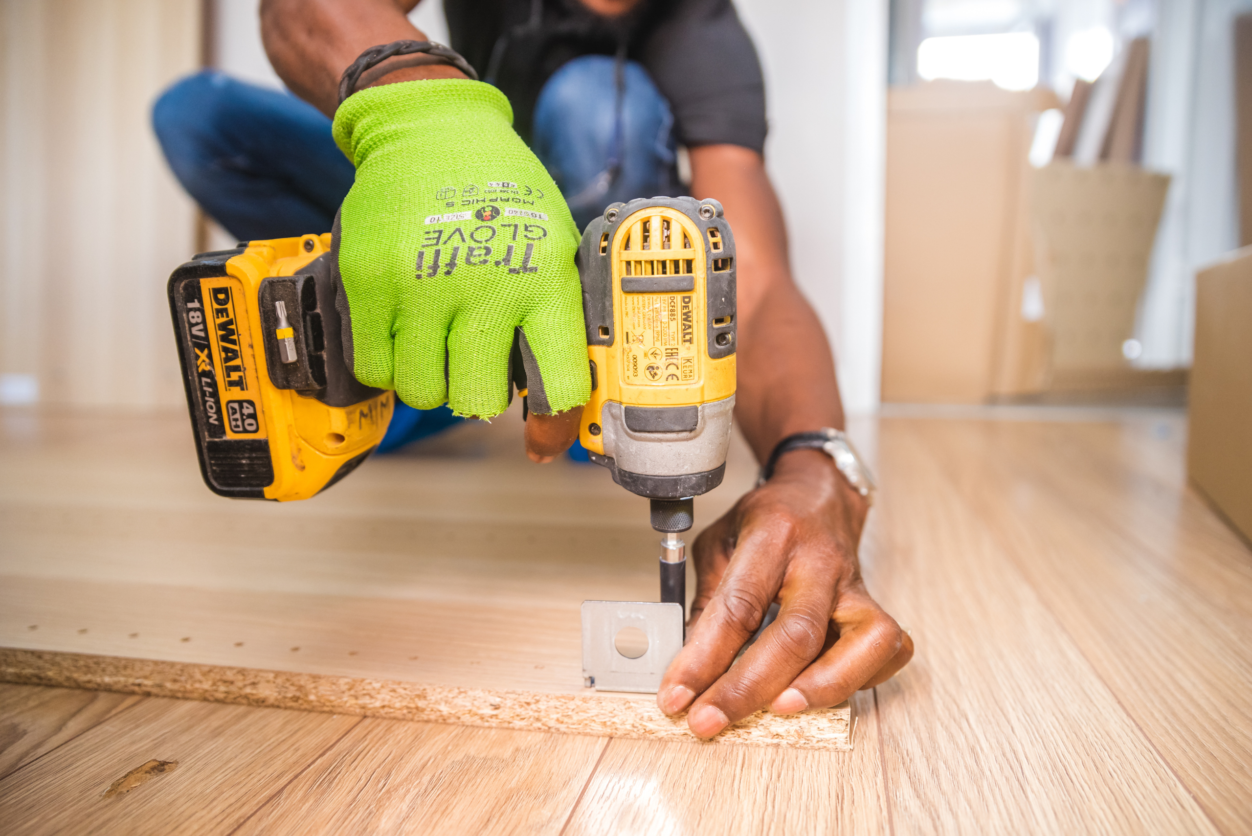 Worker wearing gloves using DeWalt impact driver.