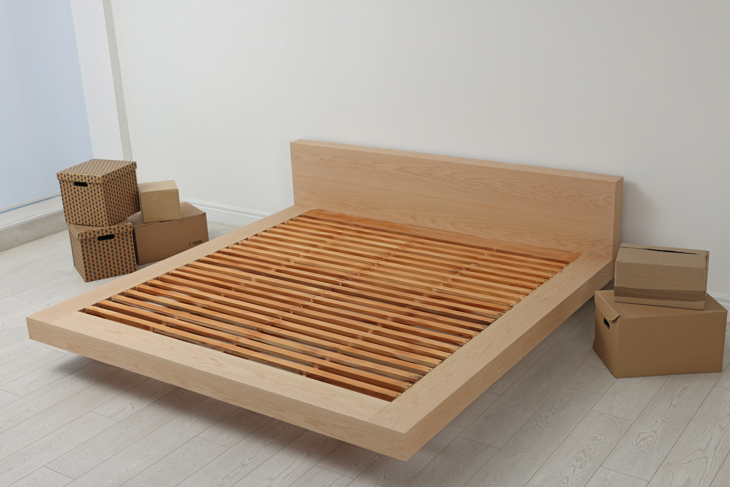 Wooden bed frame surrounded by boxes.