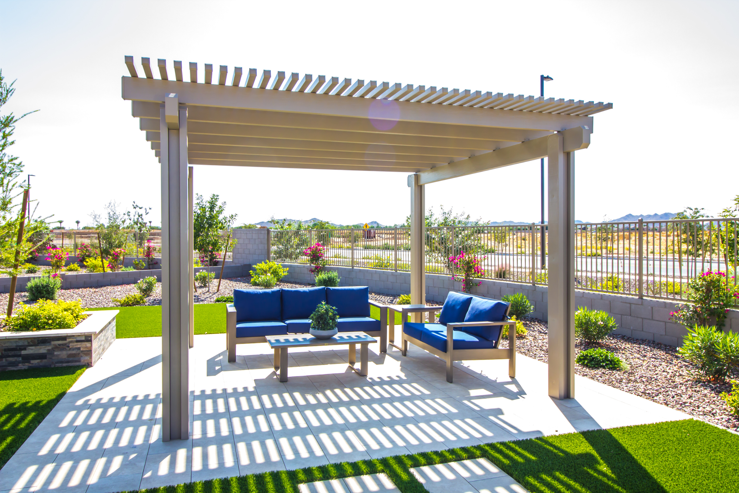 Wooden pergola on a concrete slap, covering outdoor furniture.