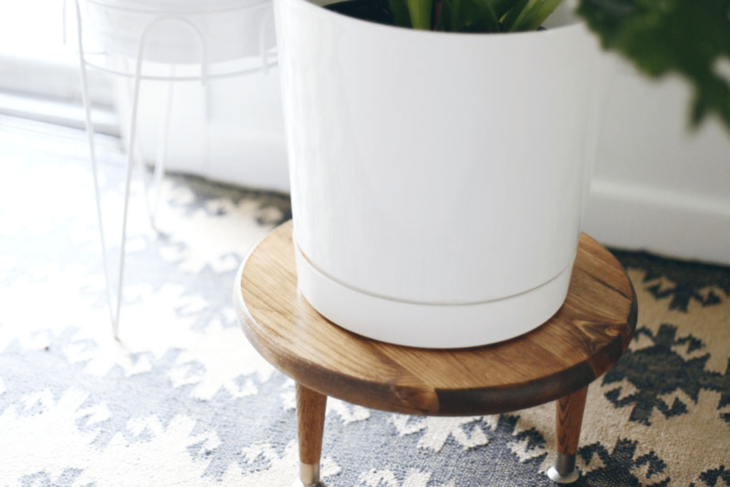 Wooden plant stand flanked by a white metal plant stand.