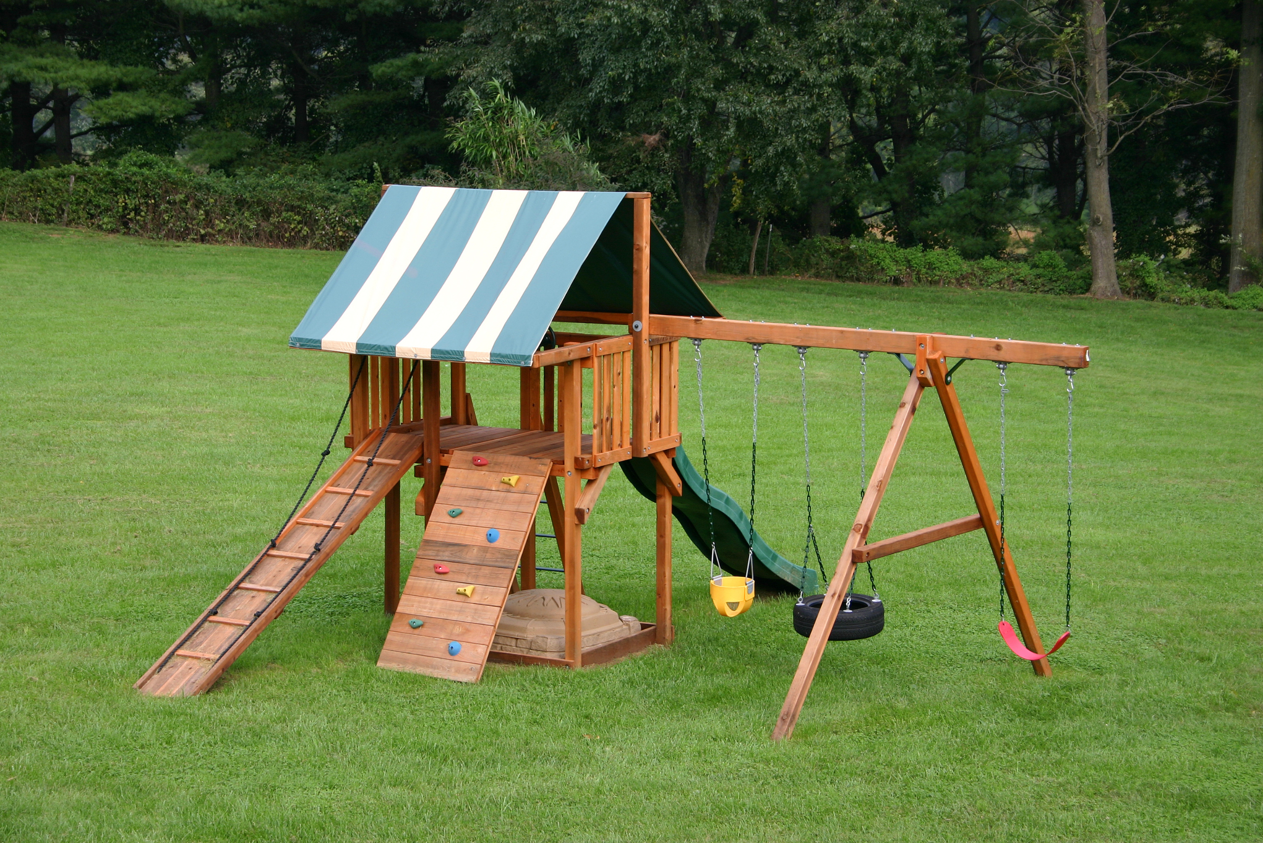 Swing set attached to a play ground, all made of wood.