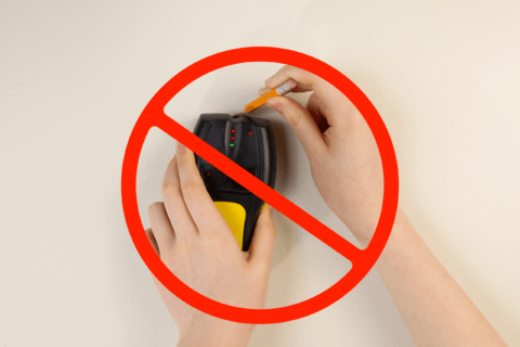 A person's hands using a stud finder and pencil overlaid with a no sign.