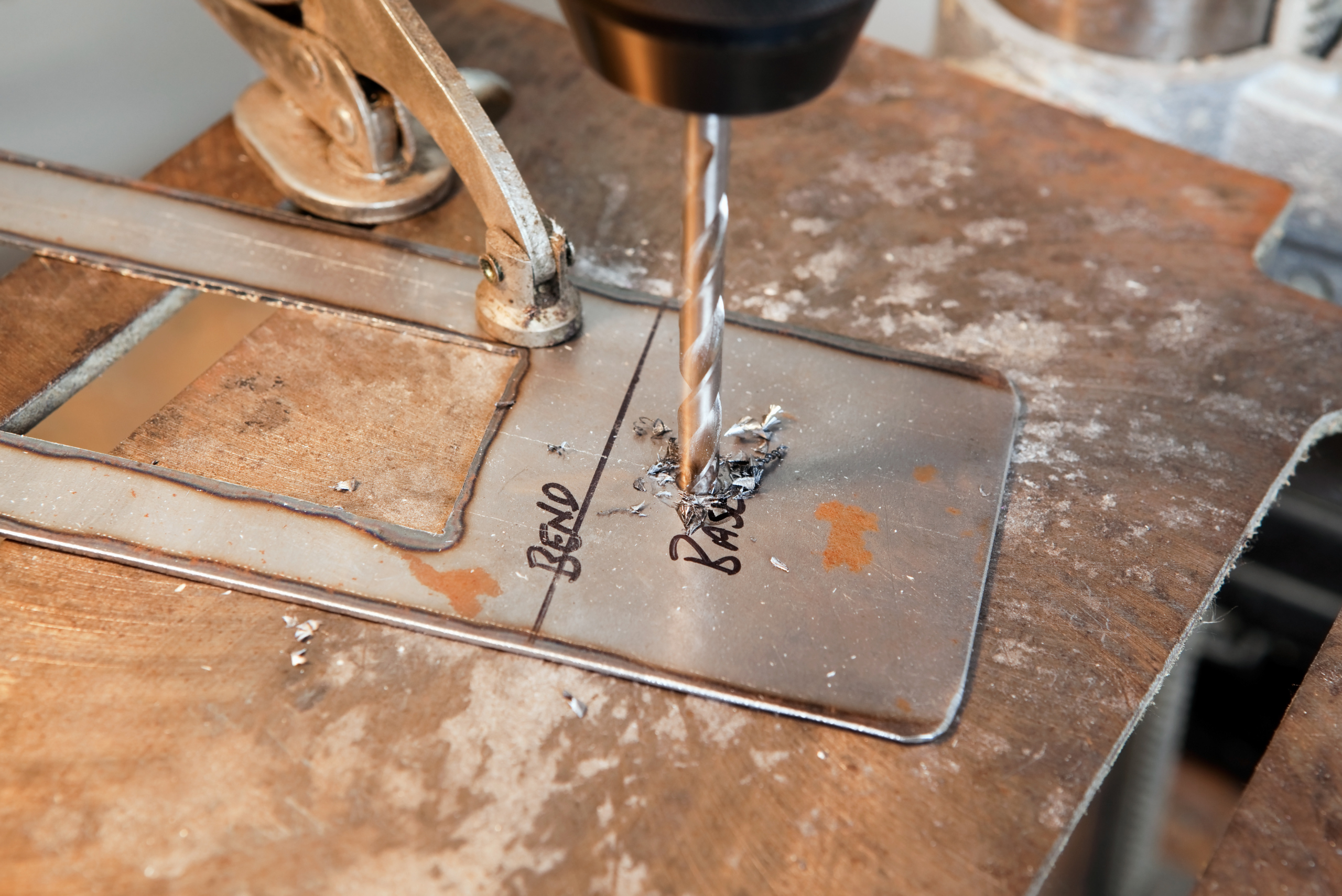 Drill press with metal drill bit creating holes in DIY project.