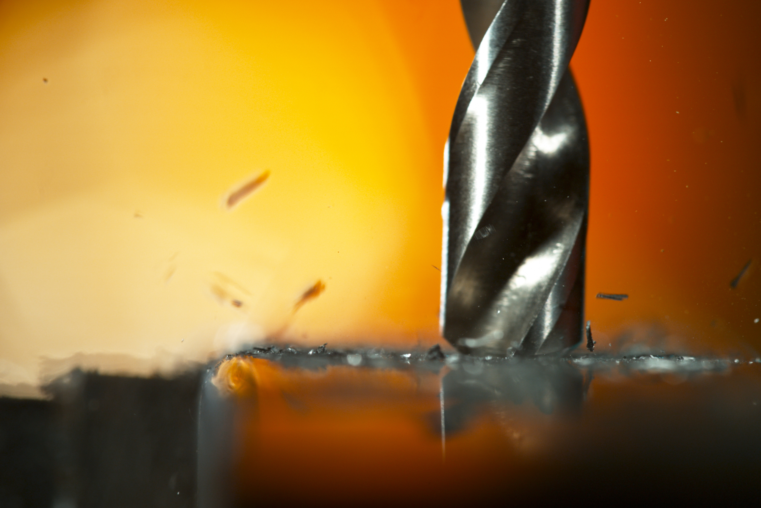 Closeup of a metal drill bit drilling into aluminum.