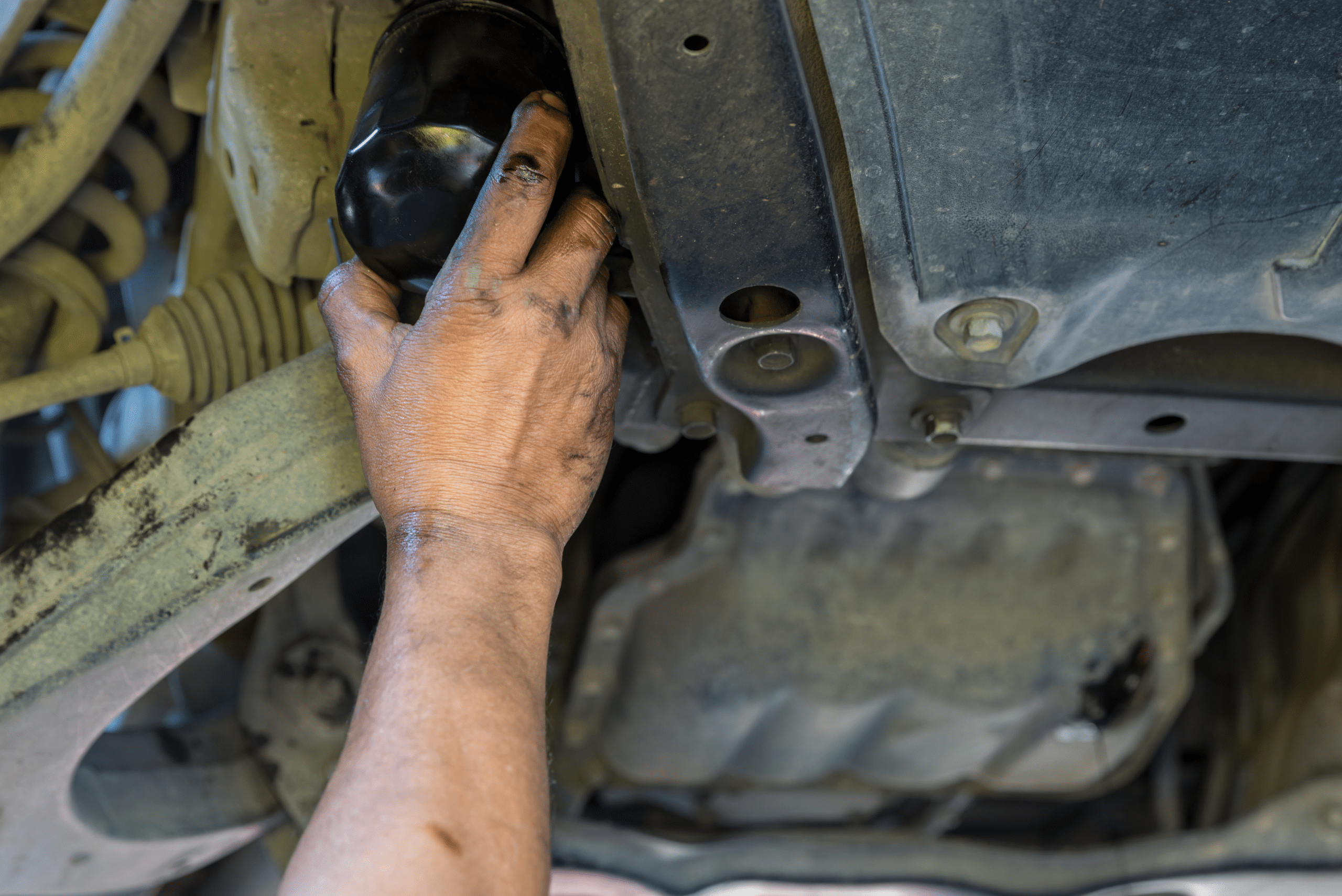 Closeup of hand removing engine oil filter.