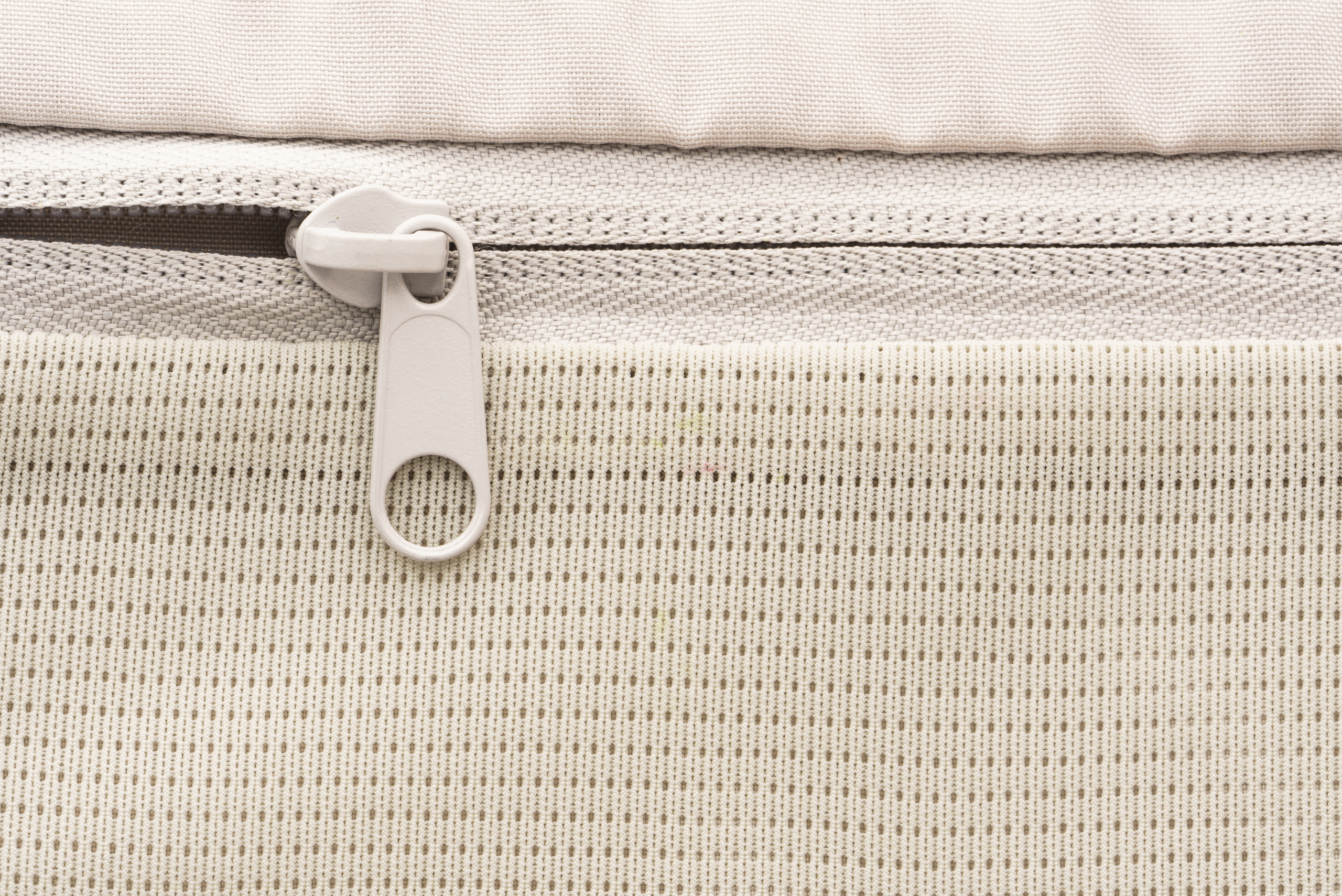 Closeup of a beige backpack zipper.