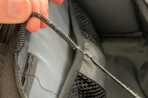 Broken backpack zipper that's ripping off the fabric.