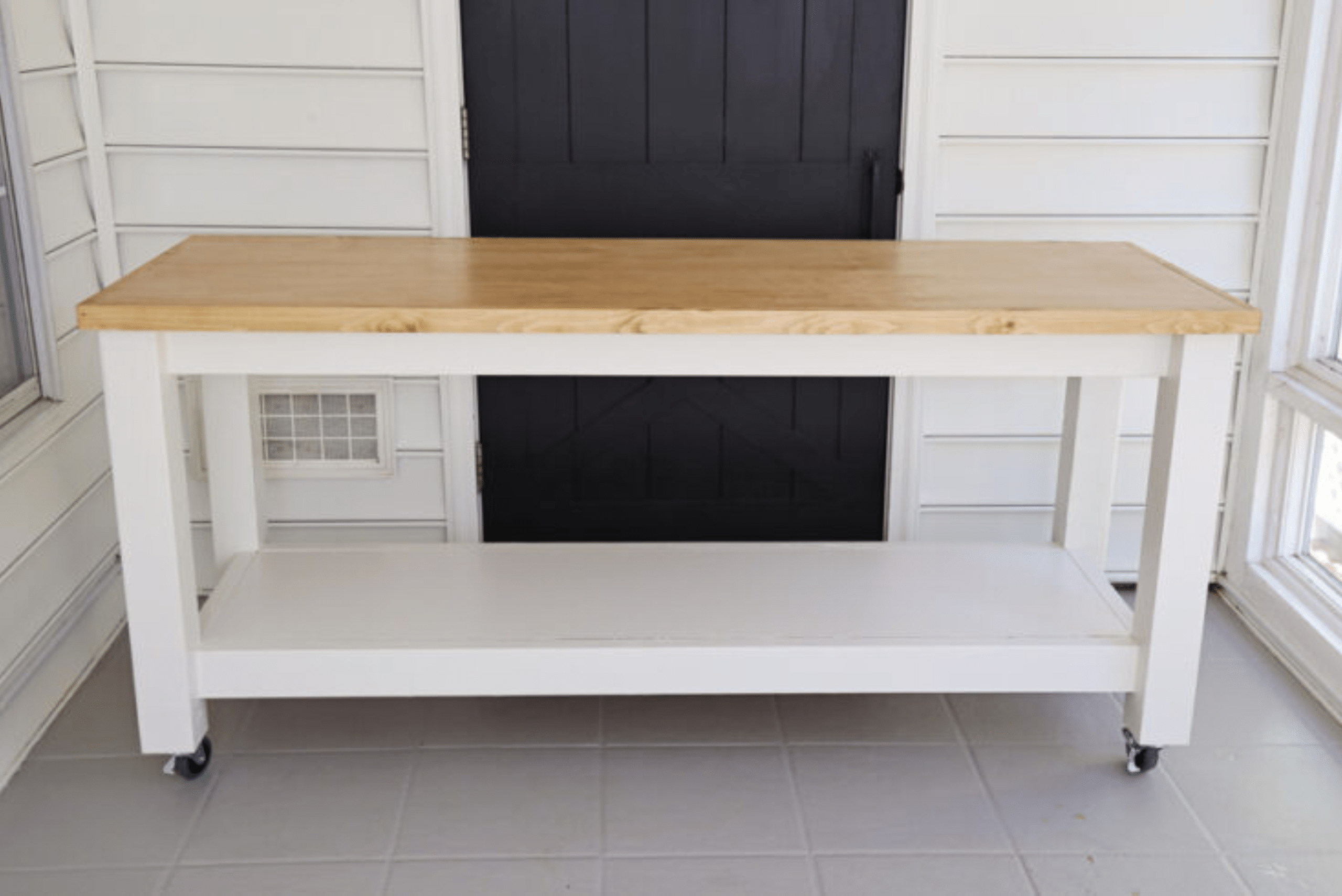 White framed workbench with hardwood top and wheels.