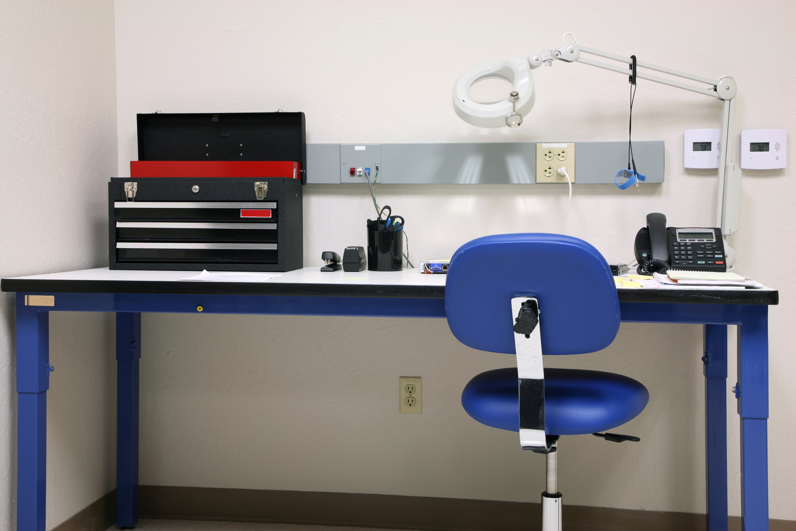 Metal framed workbench with soft wooden top that's holding a tool box among other things.