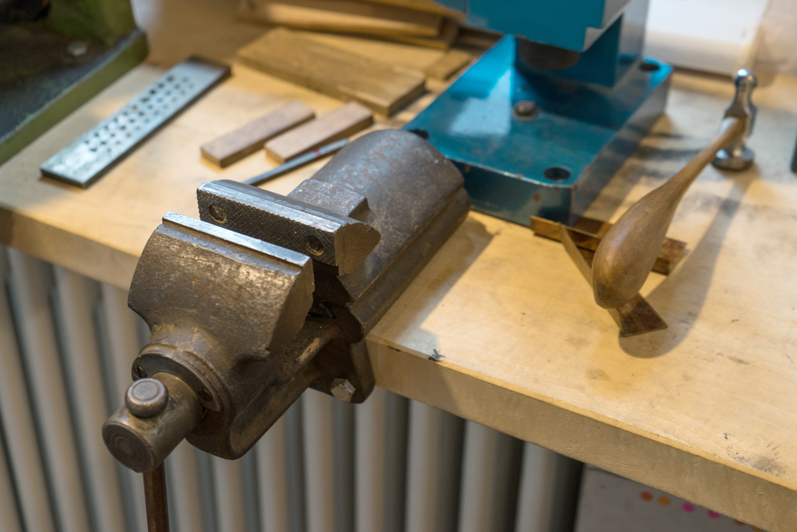 A metal vise mounted onto the wooden top of a workbench.