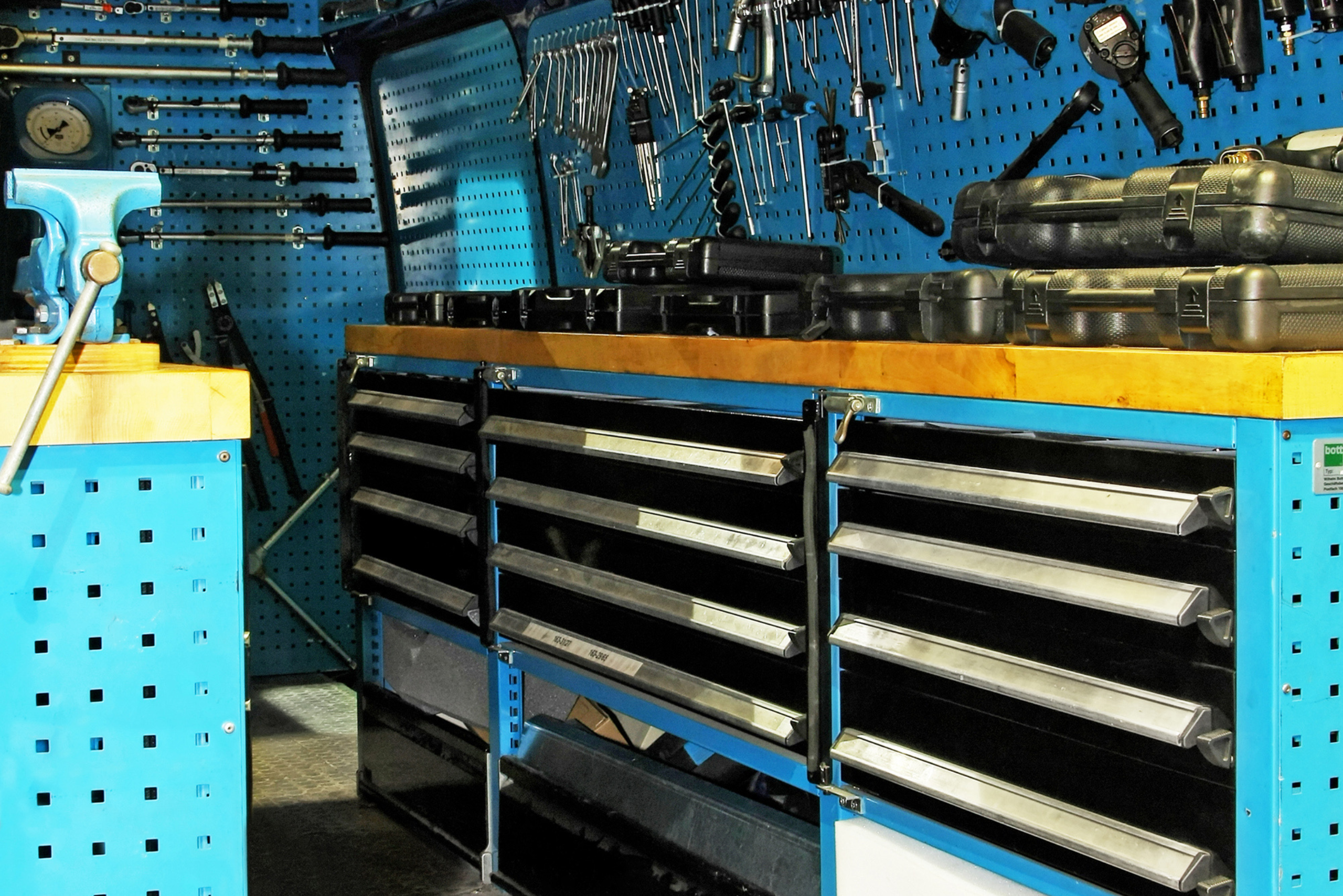 A large workbench with built-in drawers, flanked by pegboards.