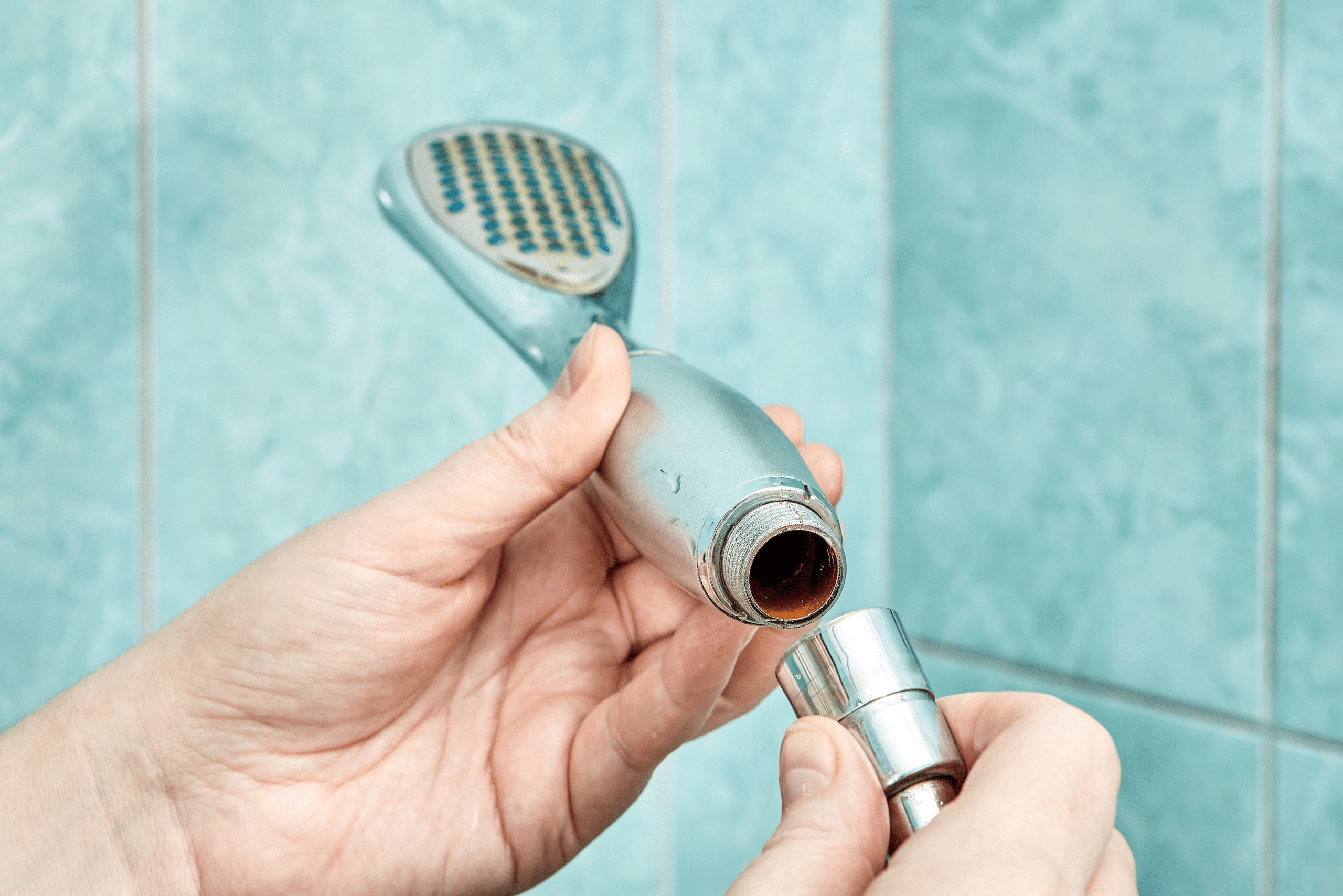 Closeup of someone's hand's threading the shower head back on.