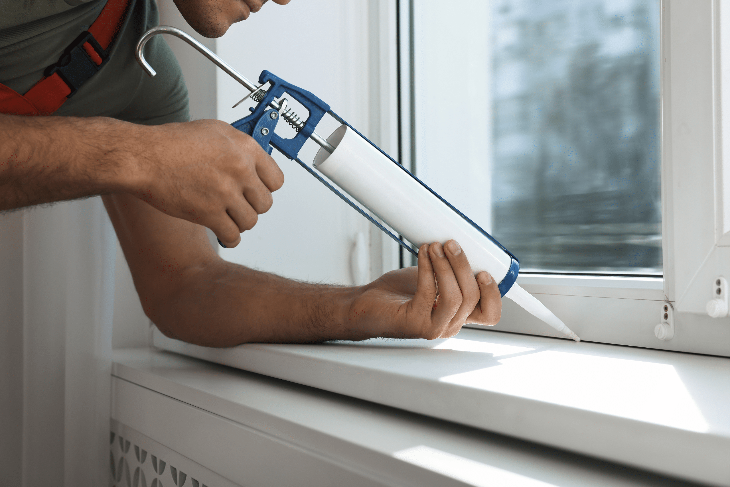 Applying caulking to window seal.