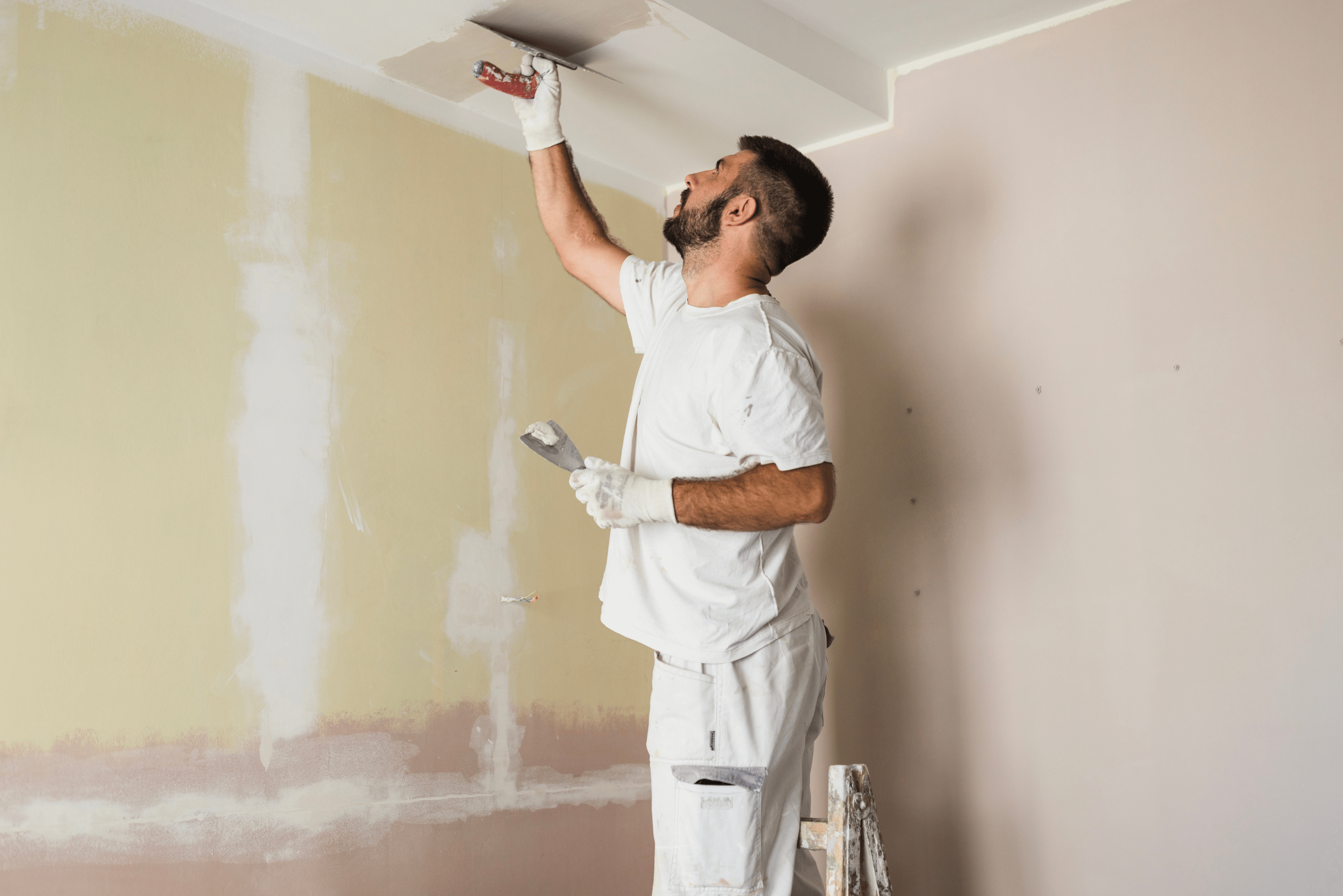 Worker preparing the ceiling for paint by evening out the surface.