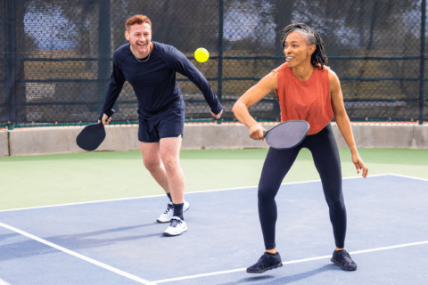 Two people playing pickleball on a court.
