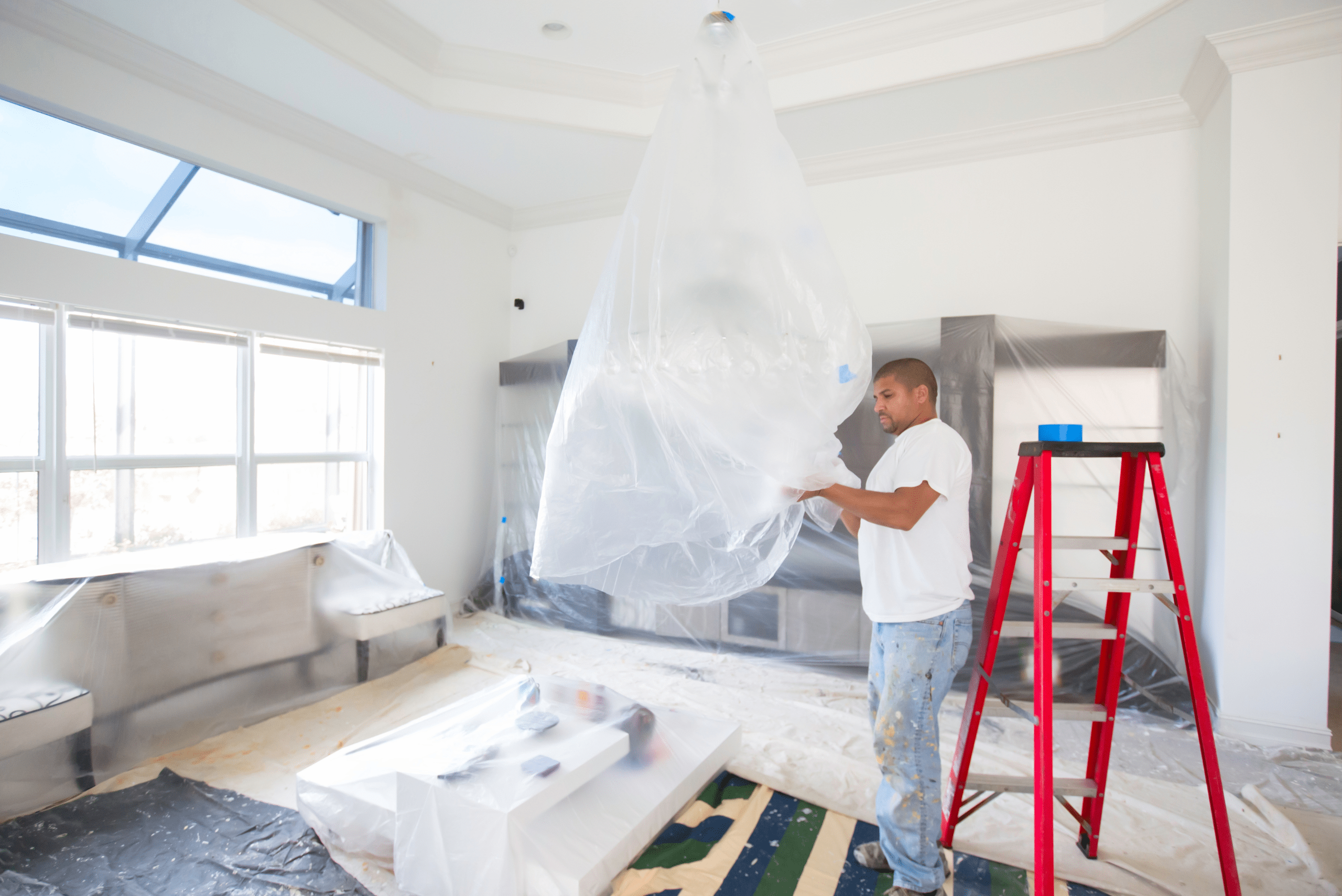 Person laying down plastic sheets to protect the room during painting.