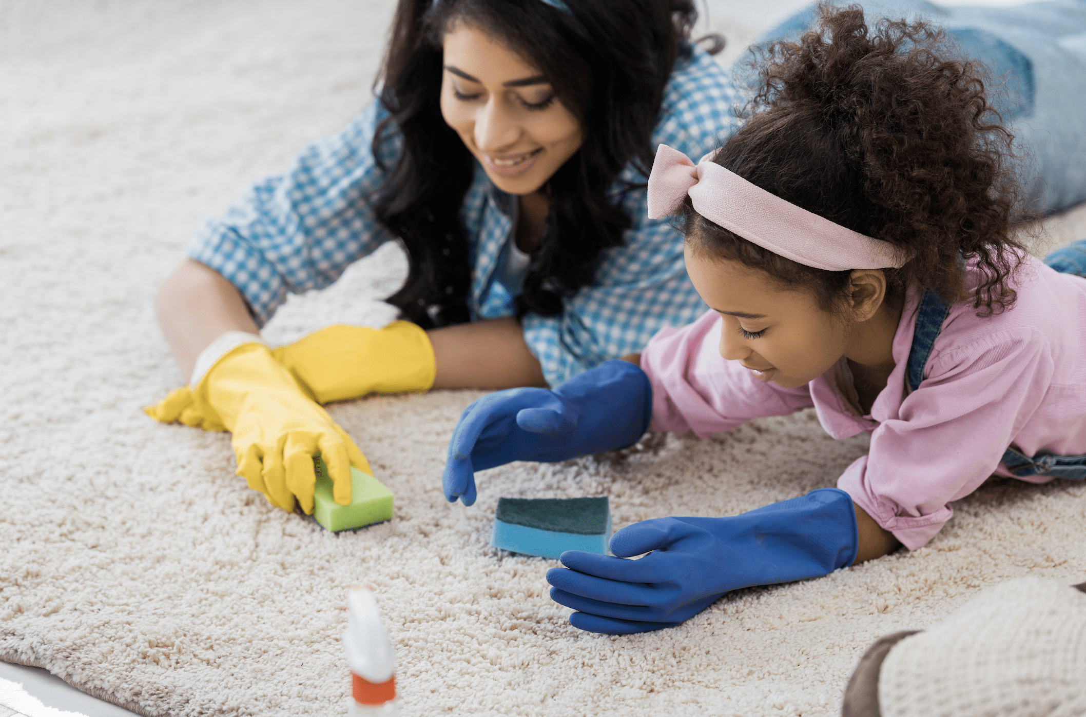 Woman and young girl using sponges on carpet.