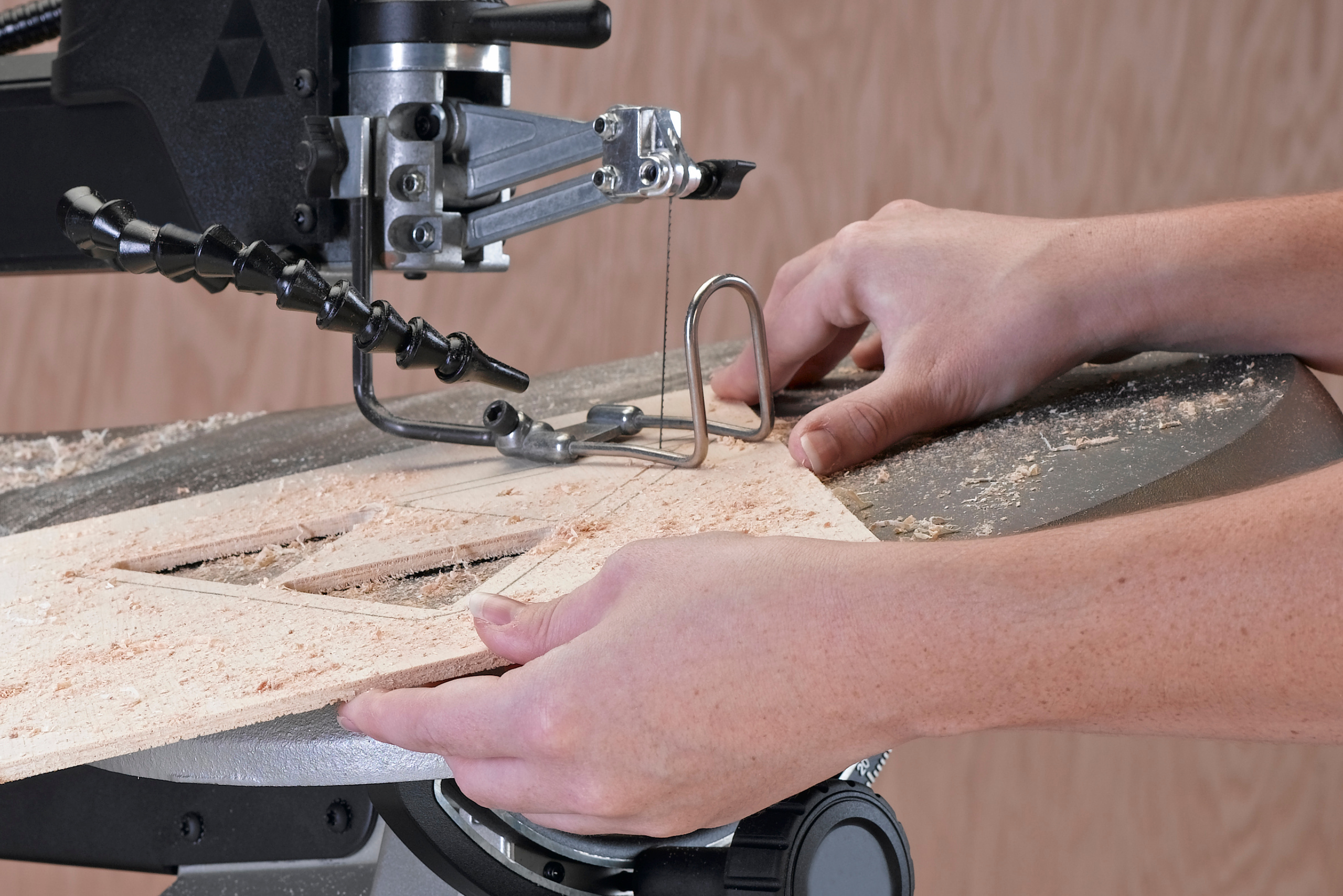 Person using scroll saw to cut wood.