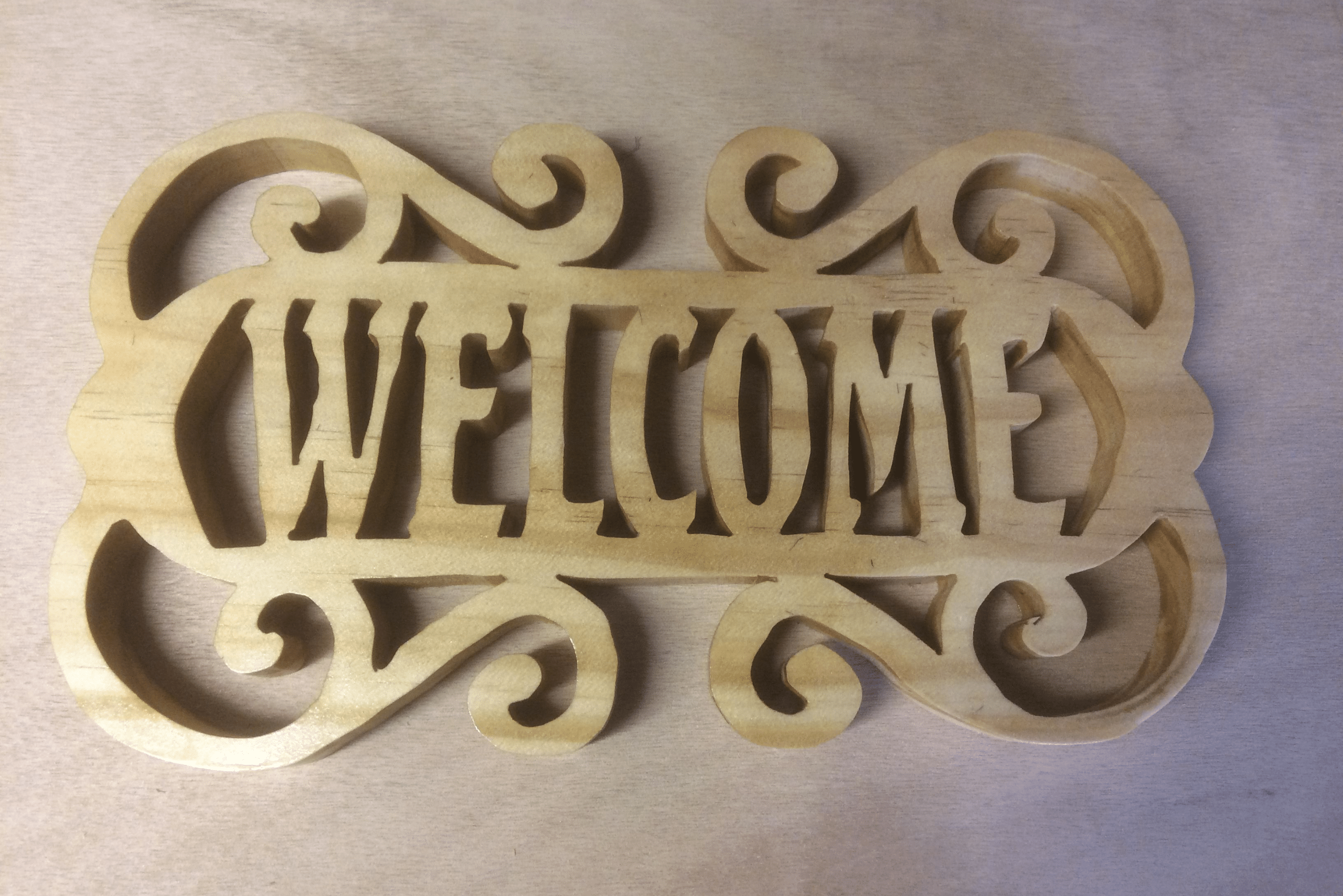 An outdoor wooden welcome sign made using a scroll saw.