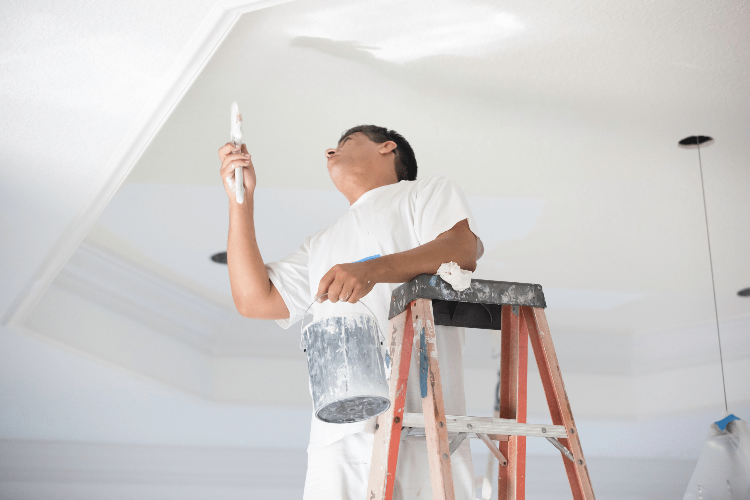 Painter touching up the paint of the ceiling.