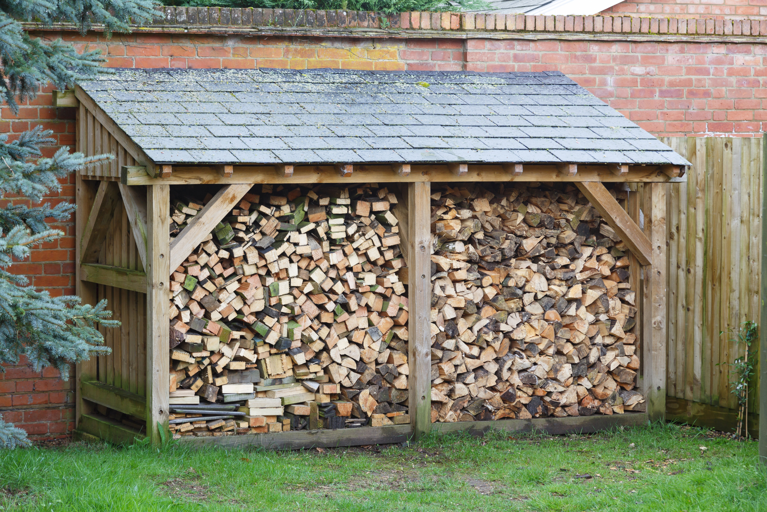 Shingled DIY firewood rack with wooden support.