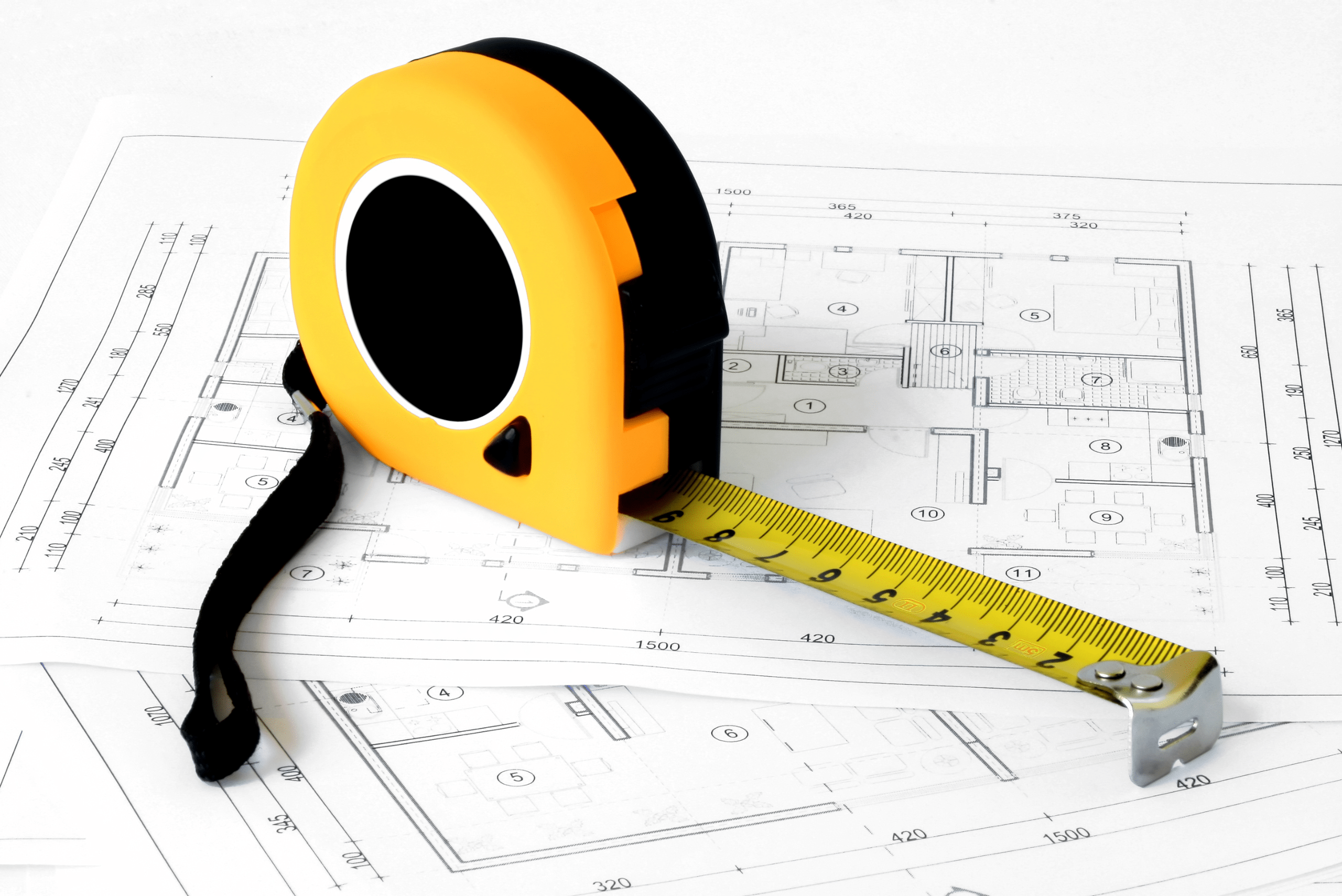 A yellow measuring tape on blueprints of rooms.