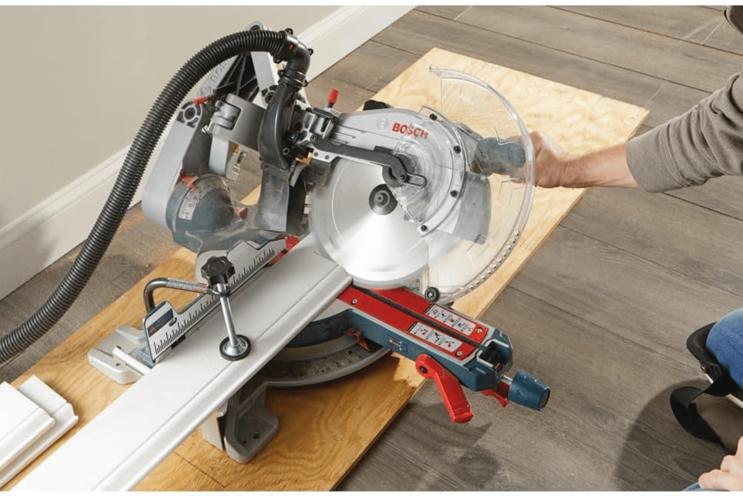 A miter saw from Bosch cutting a baseboard at an angle.