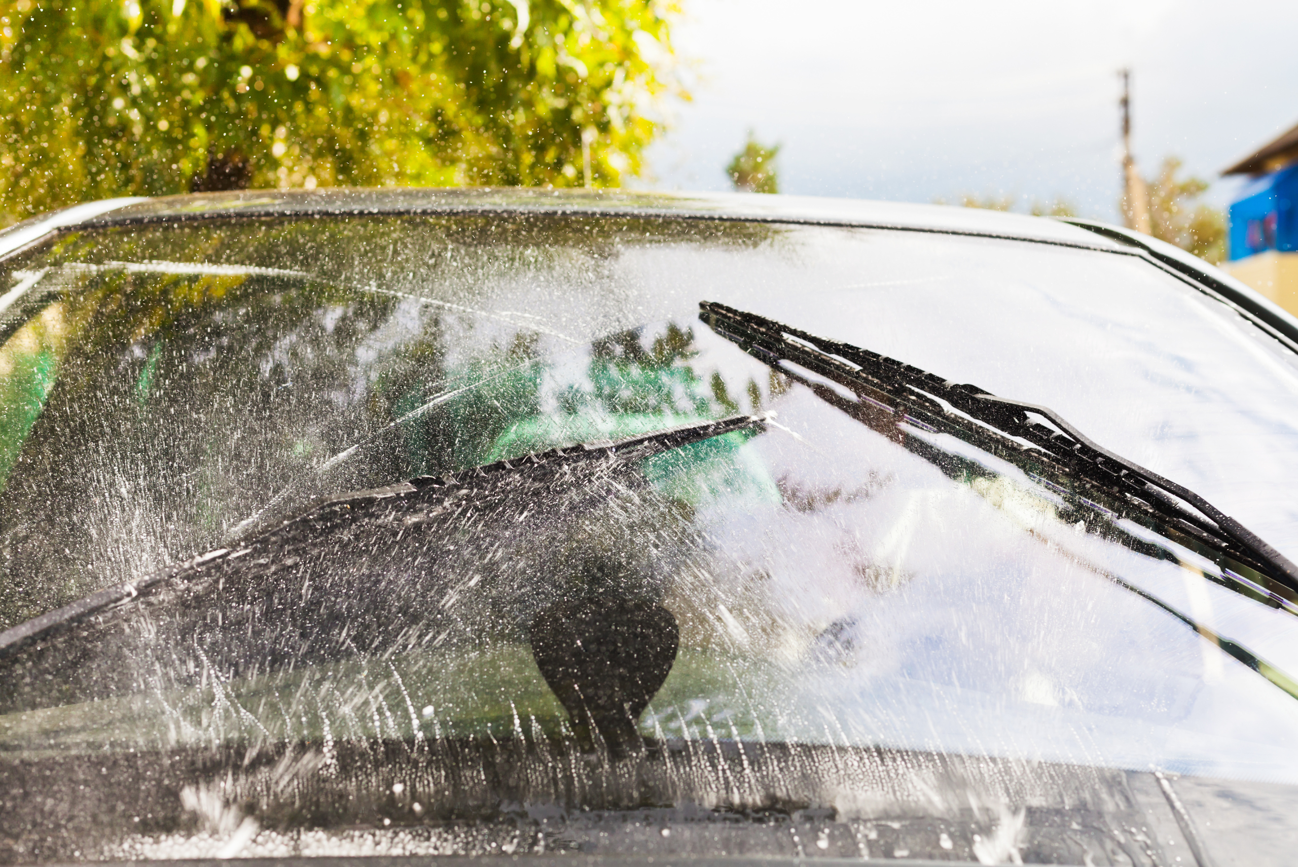 Windshield being sprayed and wipers clearing it.