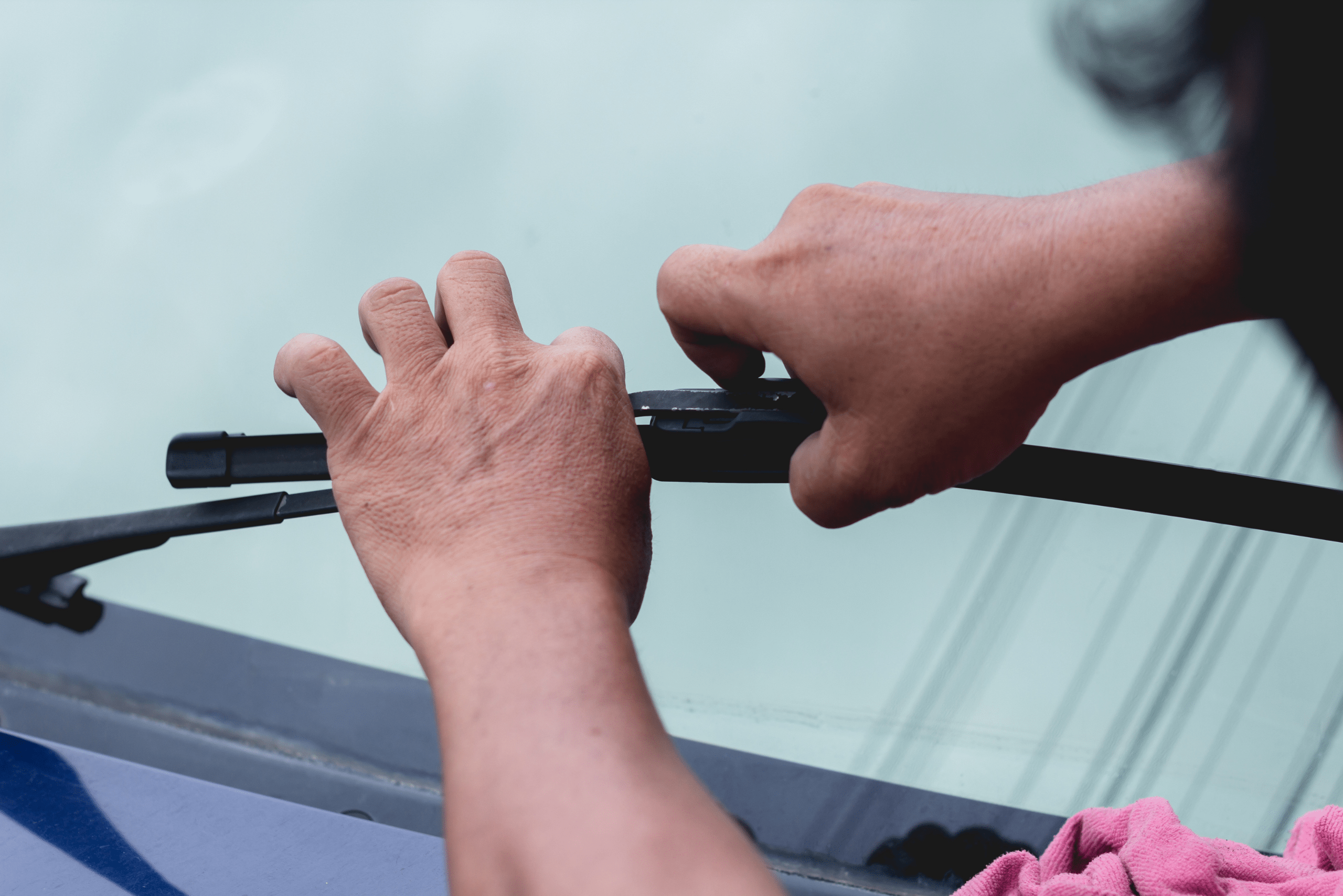 Closeup of a person's hands unhooking the wiper blade from the arm.