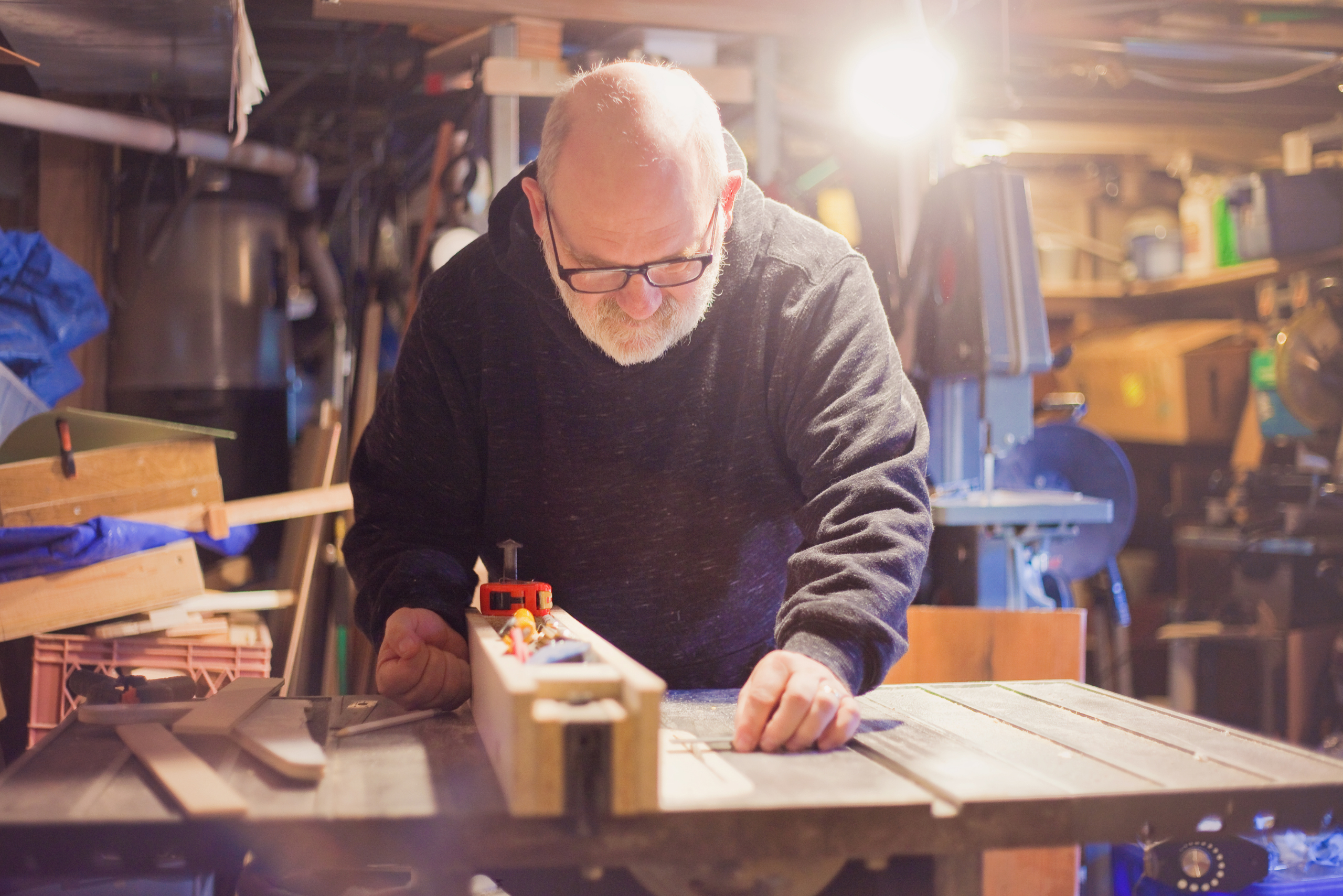 Person cutting wood in basement hobby workship.