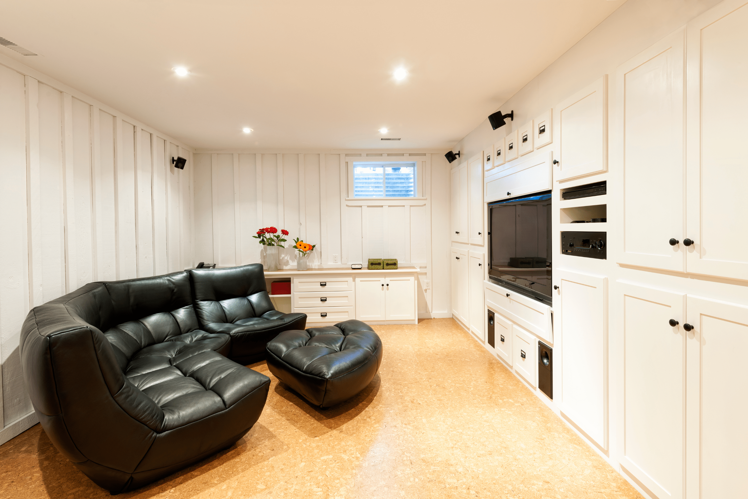 Black couch in finished basement with large TV.