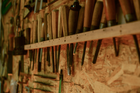 An assortment of wood carving tools mounted on wall.