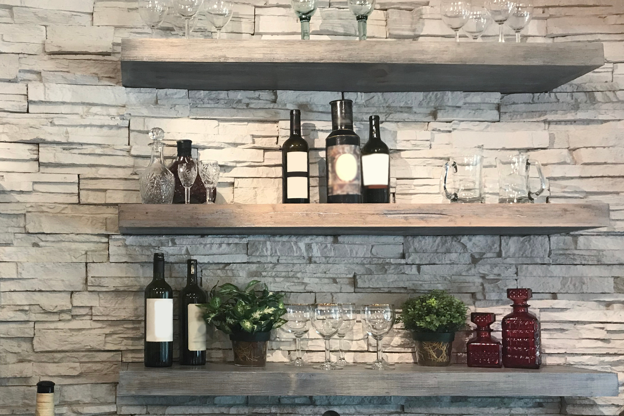 Kitchen floating shelves holding bottles and drinking glasses.