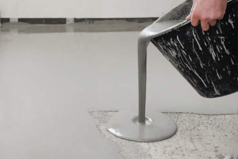Pouring self-levelling concrete from a bucket.