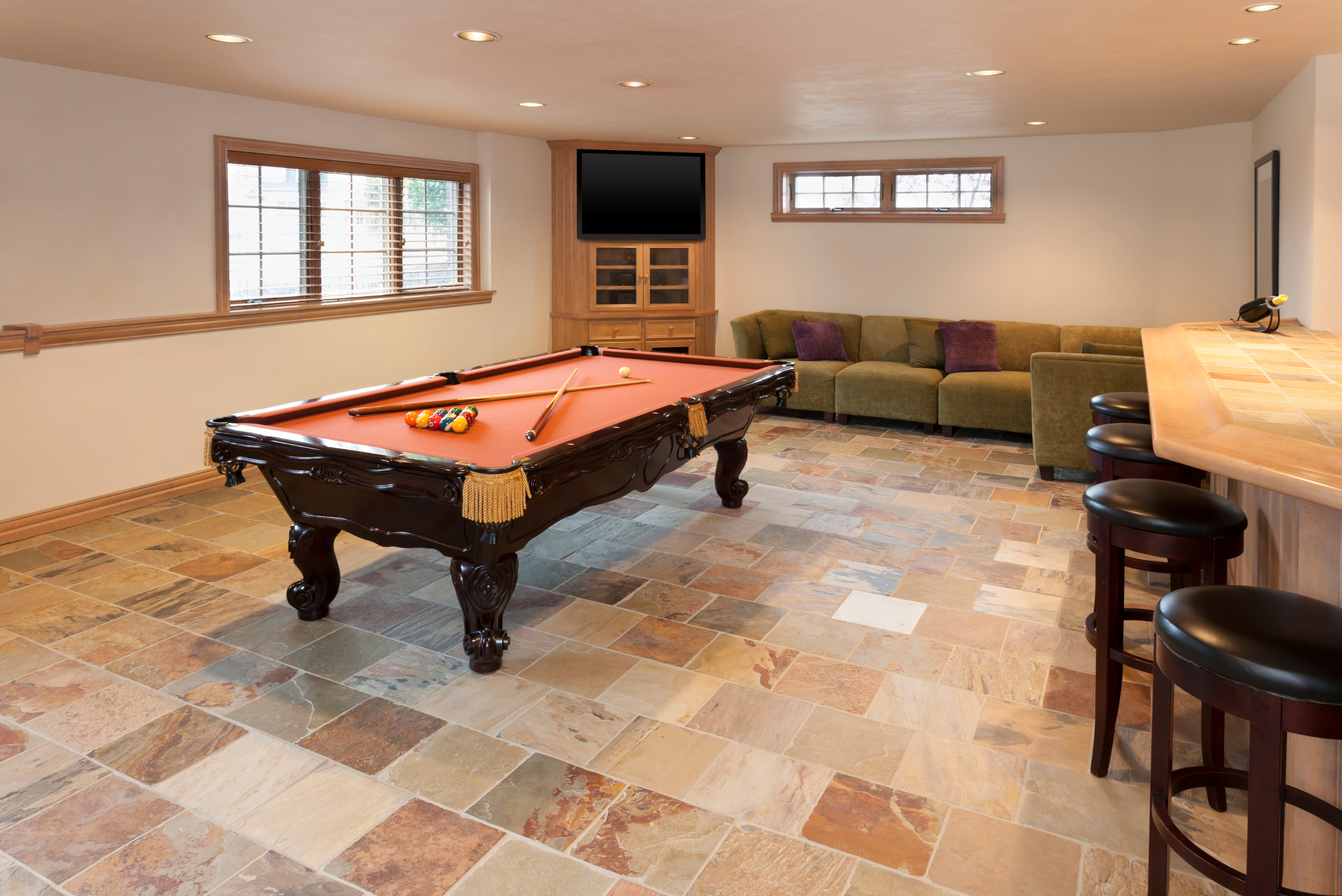 Pool table in a large finished basement with couch.
