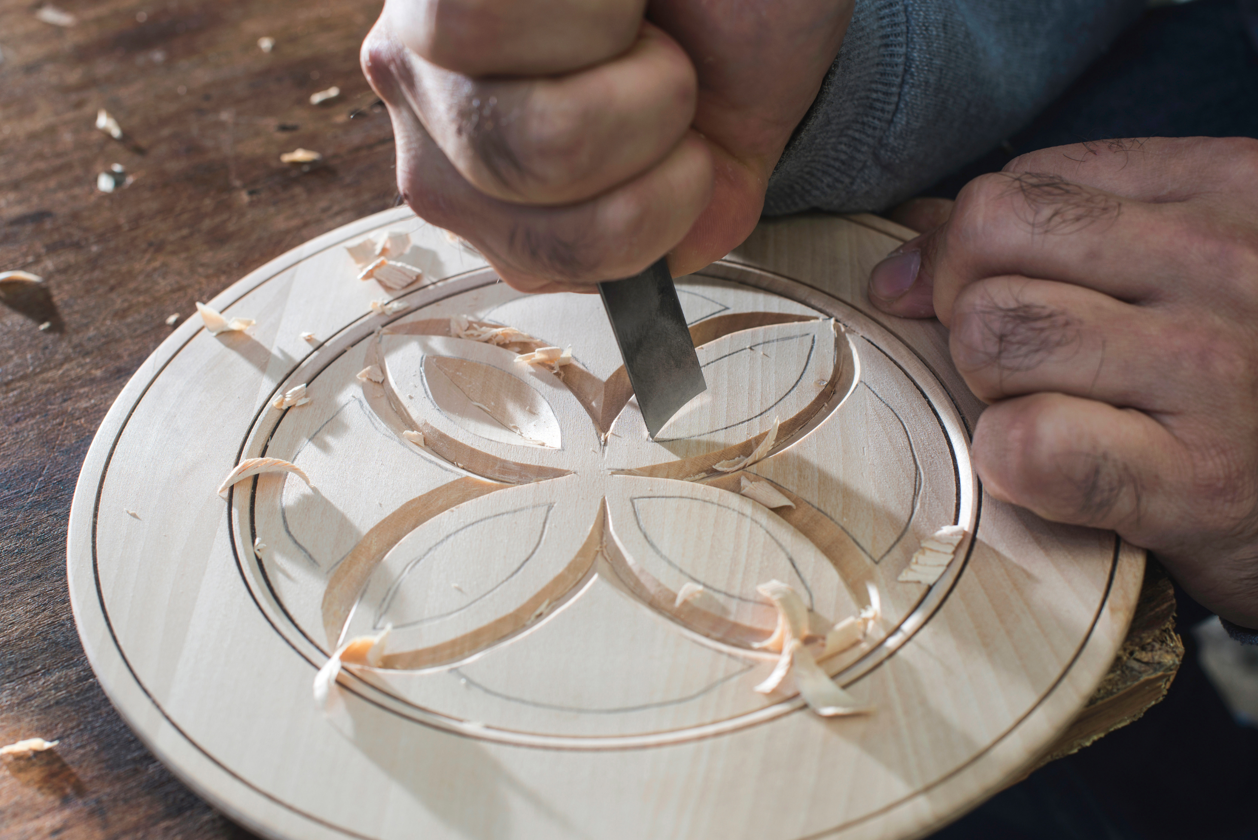 Closeup of someone's handing relief carving a flower.