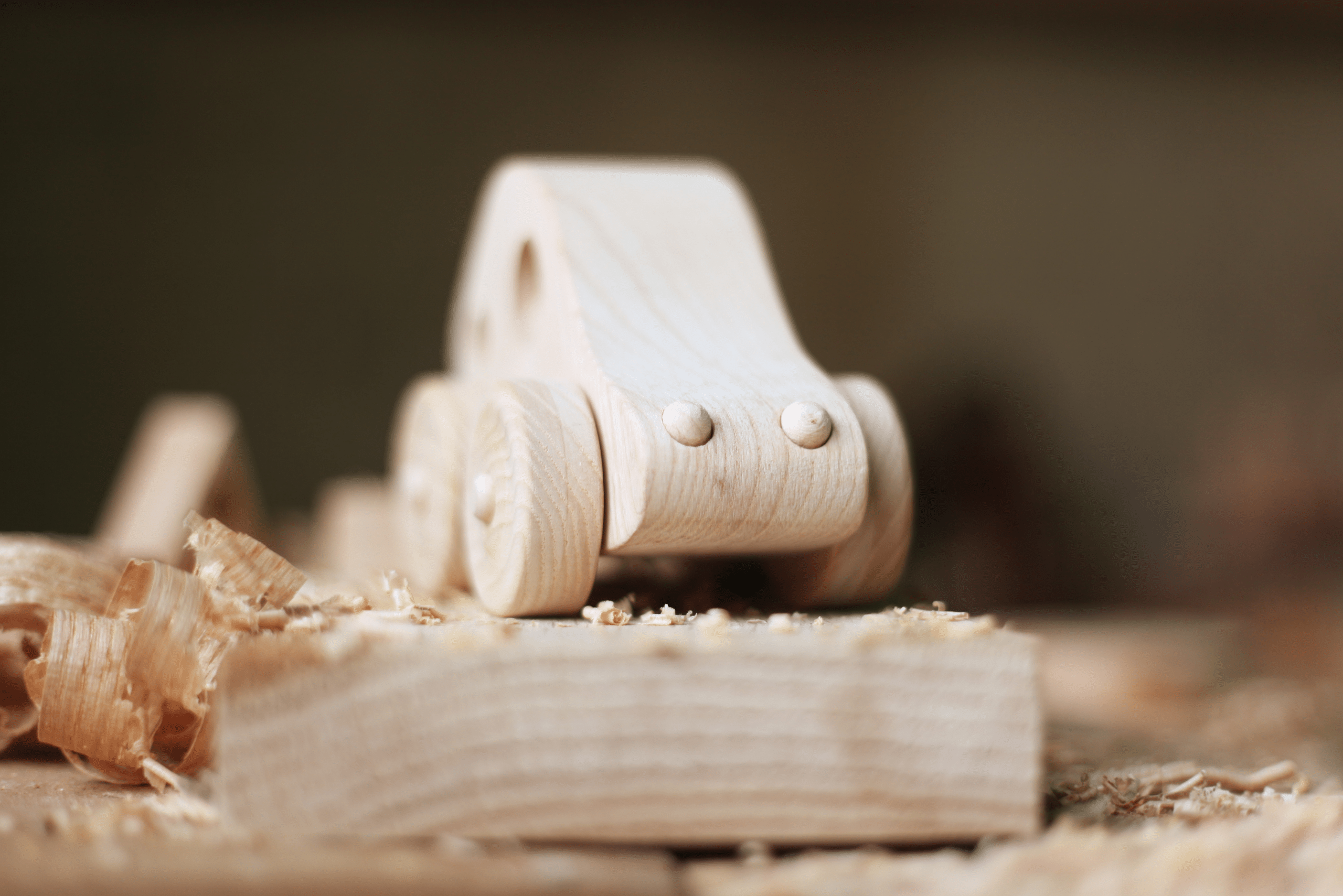 A car toy carved of wood on top of a wooden board.