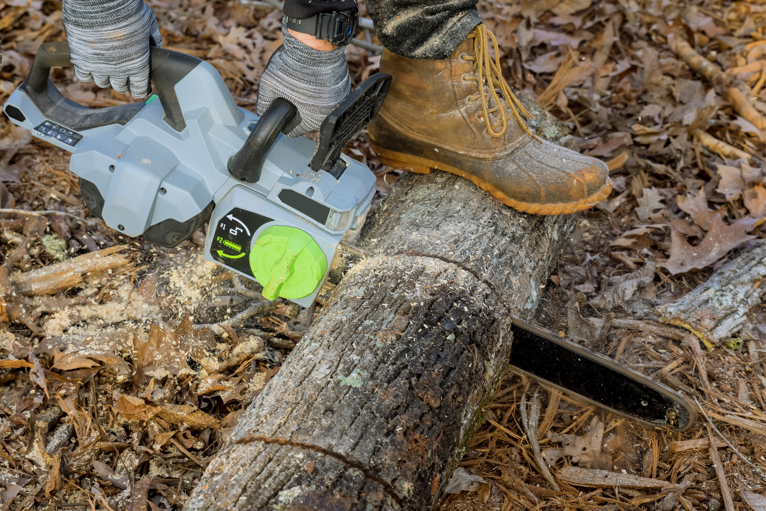 Person using battery chainsaw to cut tree.