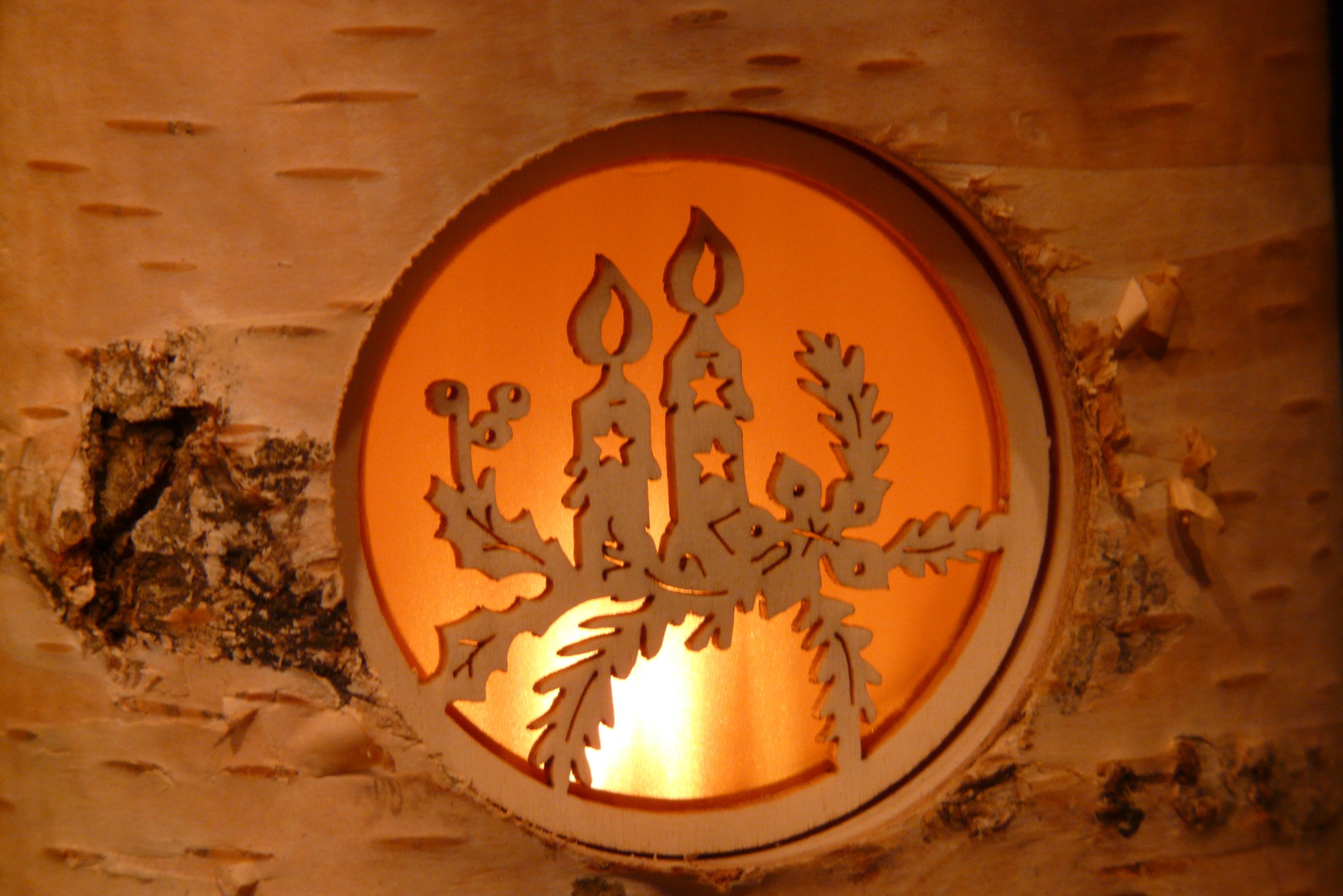 Candle carved in wood with a circular surround flanked by a fire.
