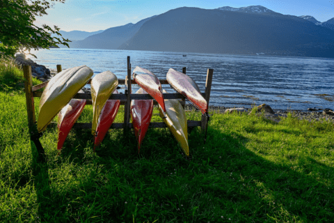 A DIY kayak rack on grass flanked by lake and mountain.