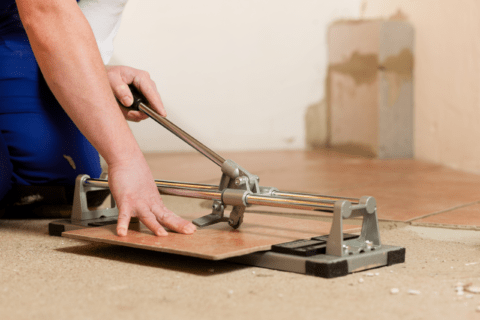 Closeup of a person using a manual tile cutter.