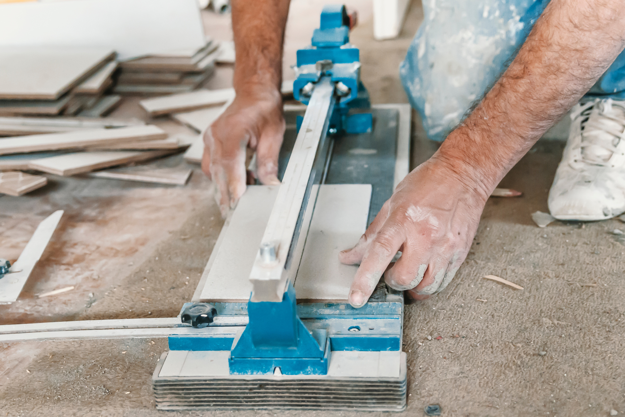 Person lining up a tile on a manual cutter.