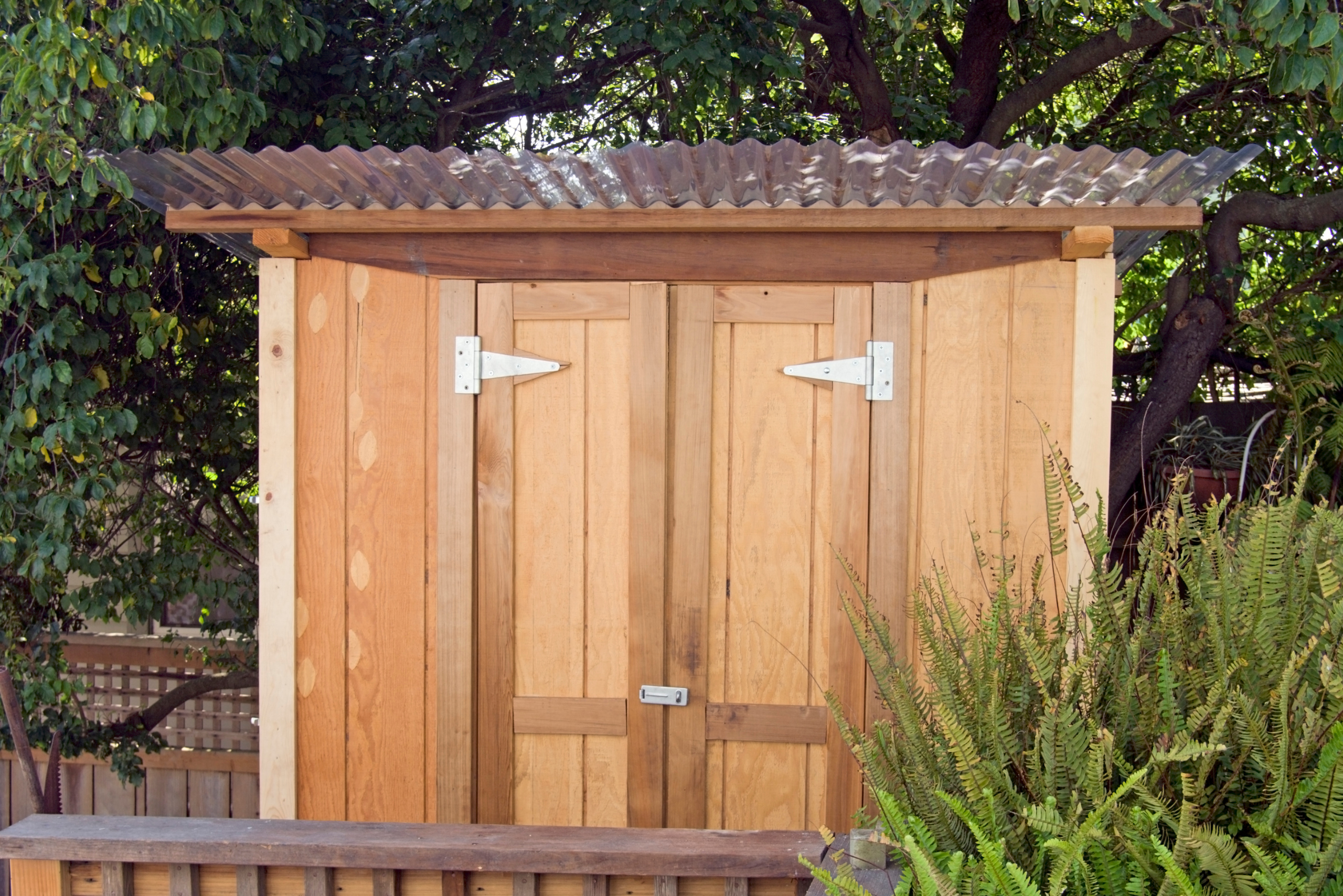 An outdoor wooden shed with double swinging doors.