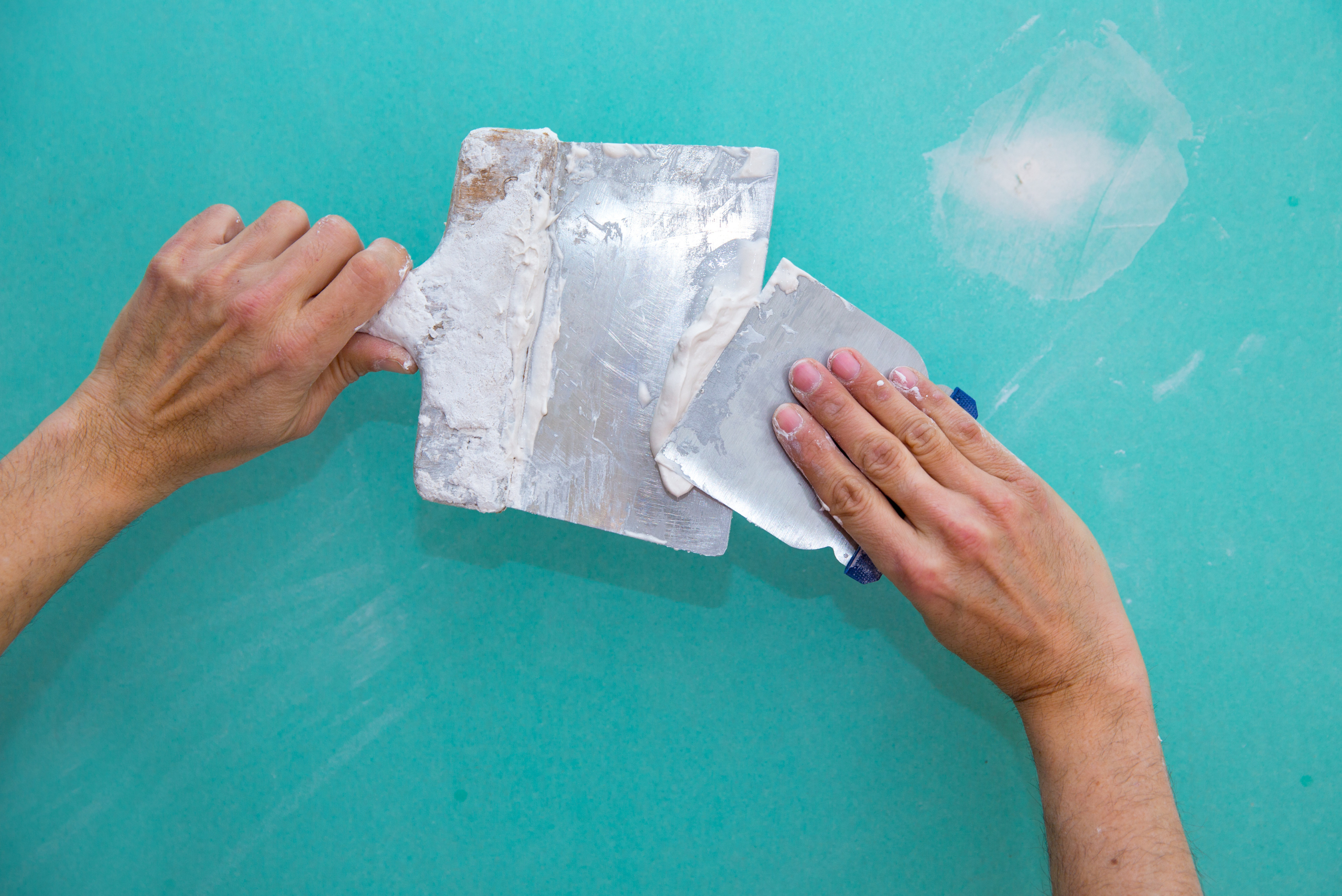 Closeup of someone's handing mixing drywall compound.