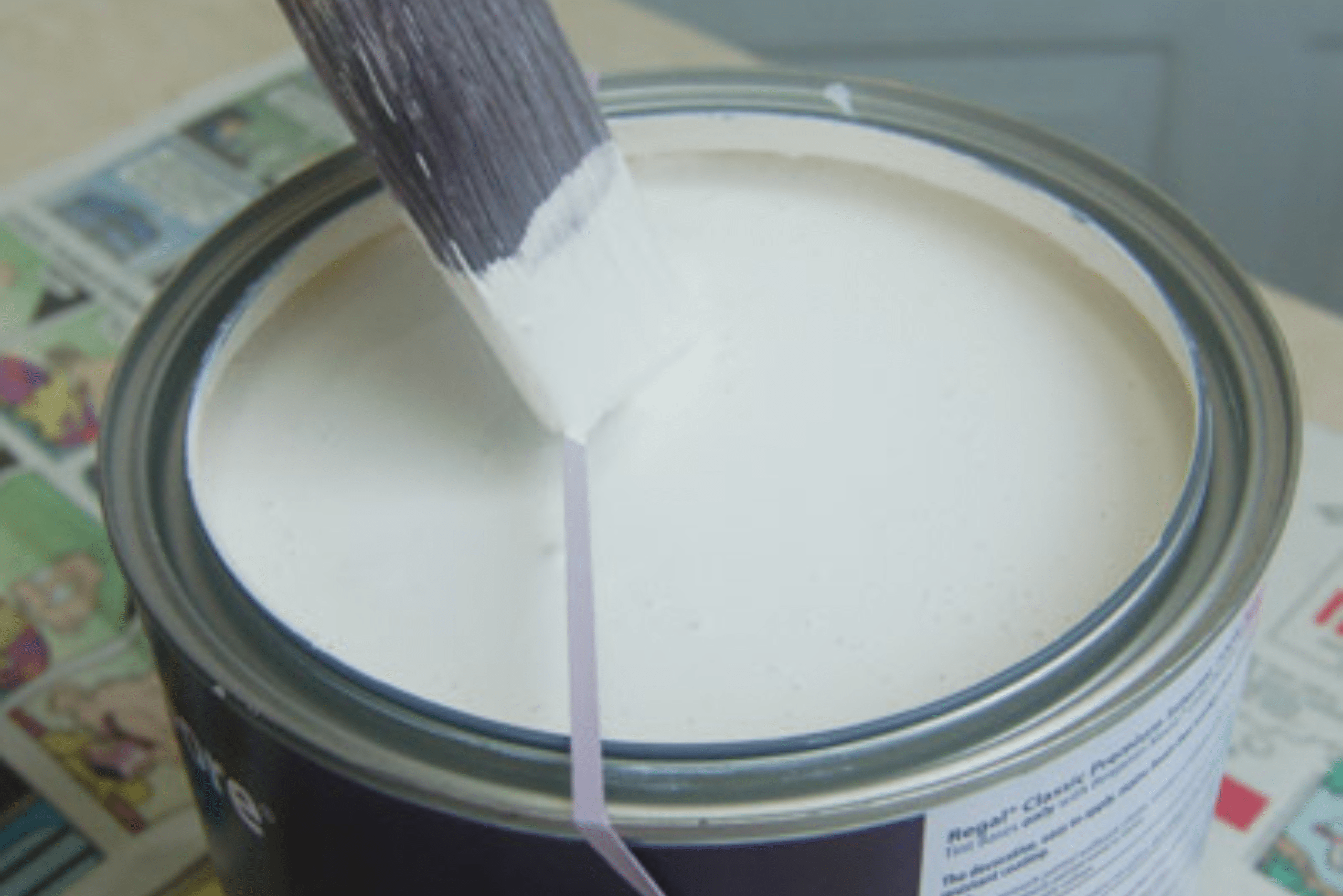 Brush being wiped on a rubber band mounted onto paint can.