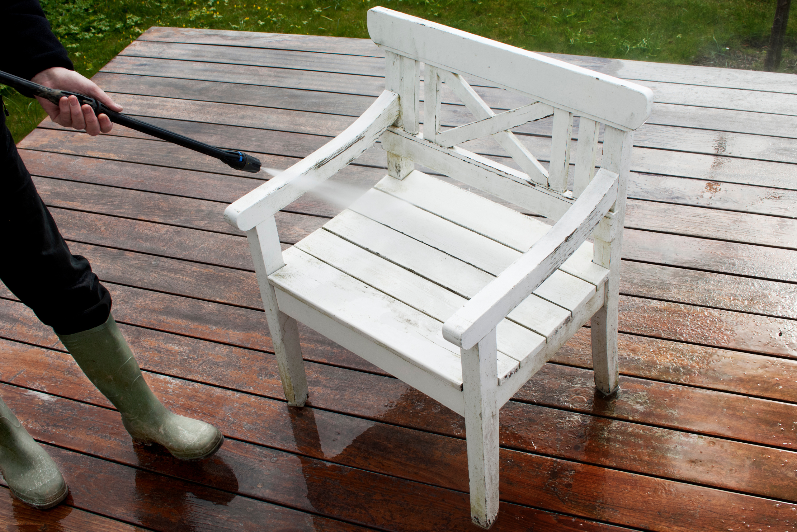Cleaning white patio chair with pressure washer.