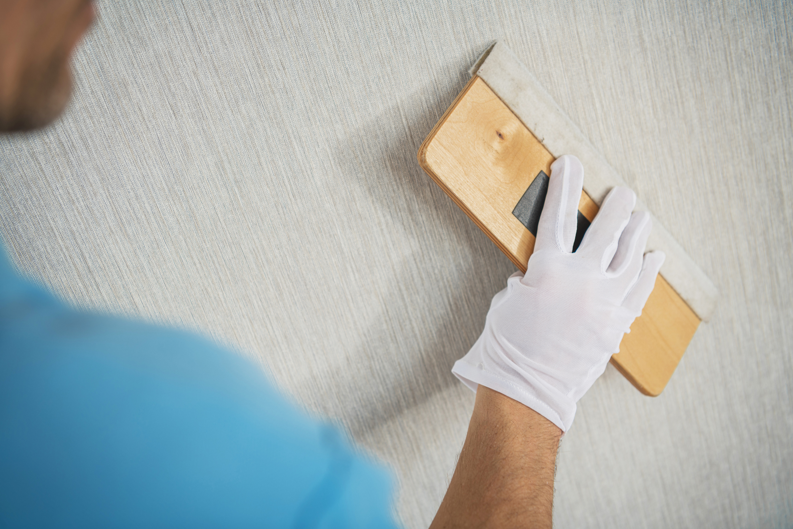 A closeup of someone using a plastic squeegee on wallpaper.